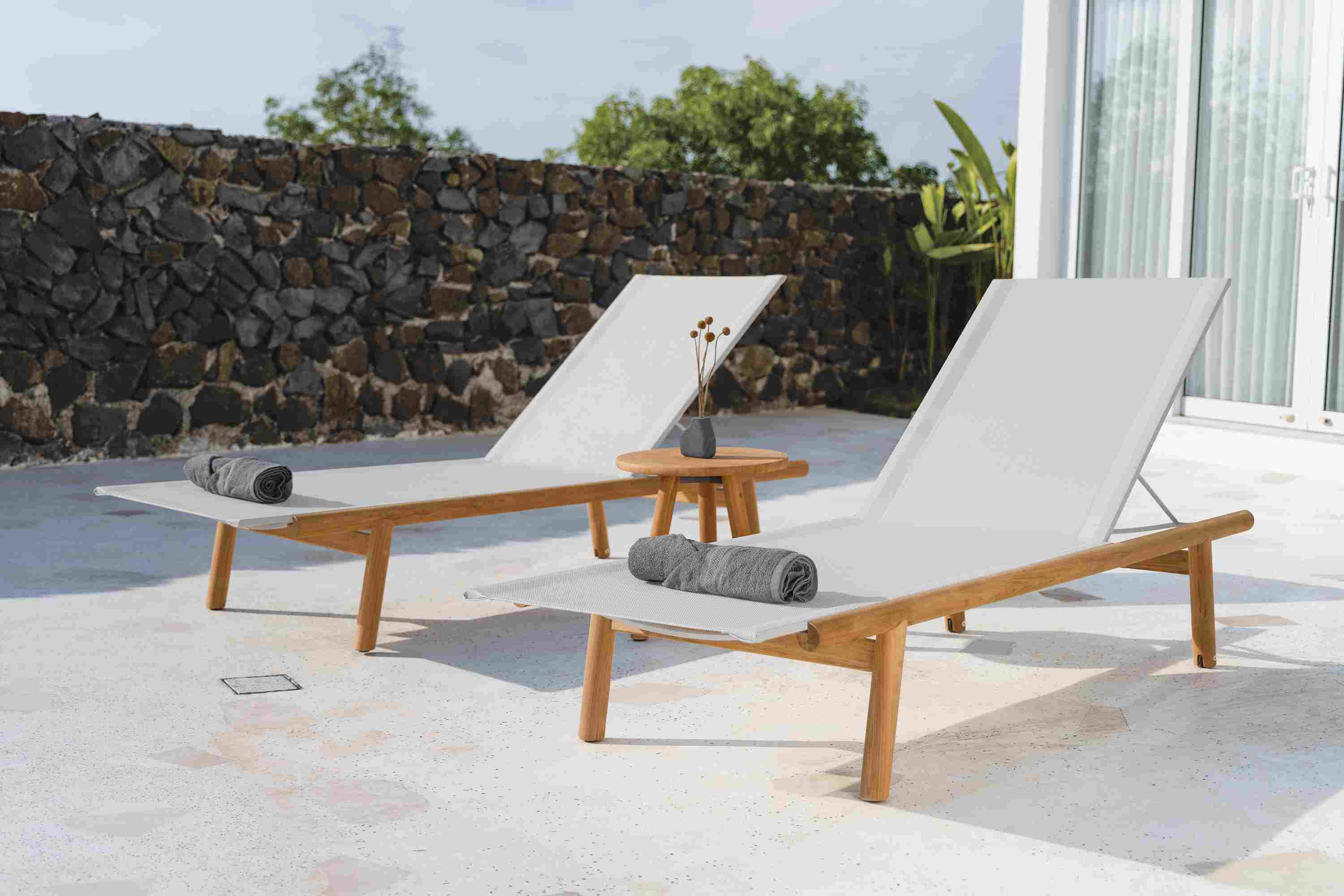 Outdoor patio with two Isley Chaises in Teak with Salt Sling with a 17-round Isley table.