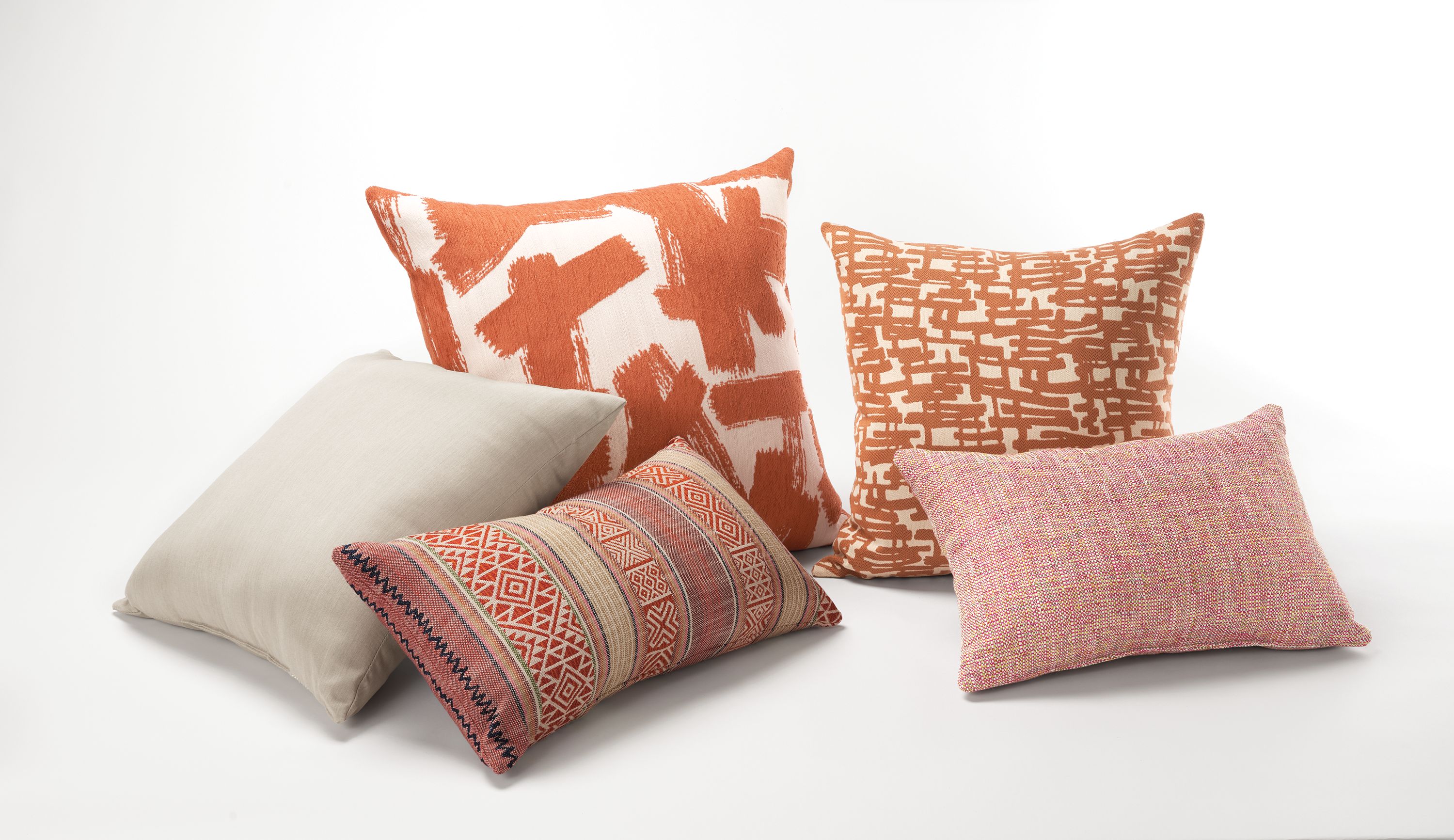 Group of pillows including Ivan, Hue, Yates, Geneva and Estes in oranges, pinks, reds and tan.