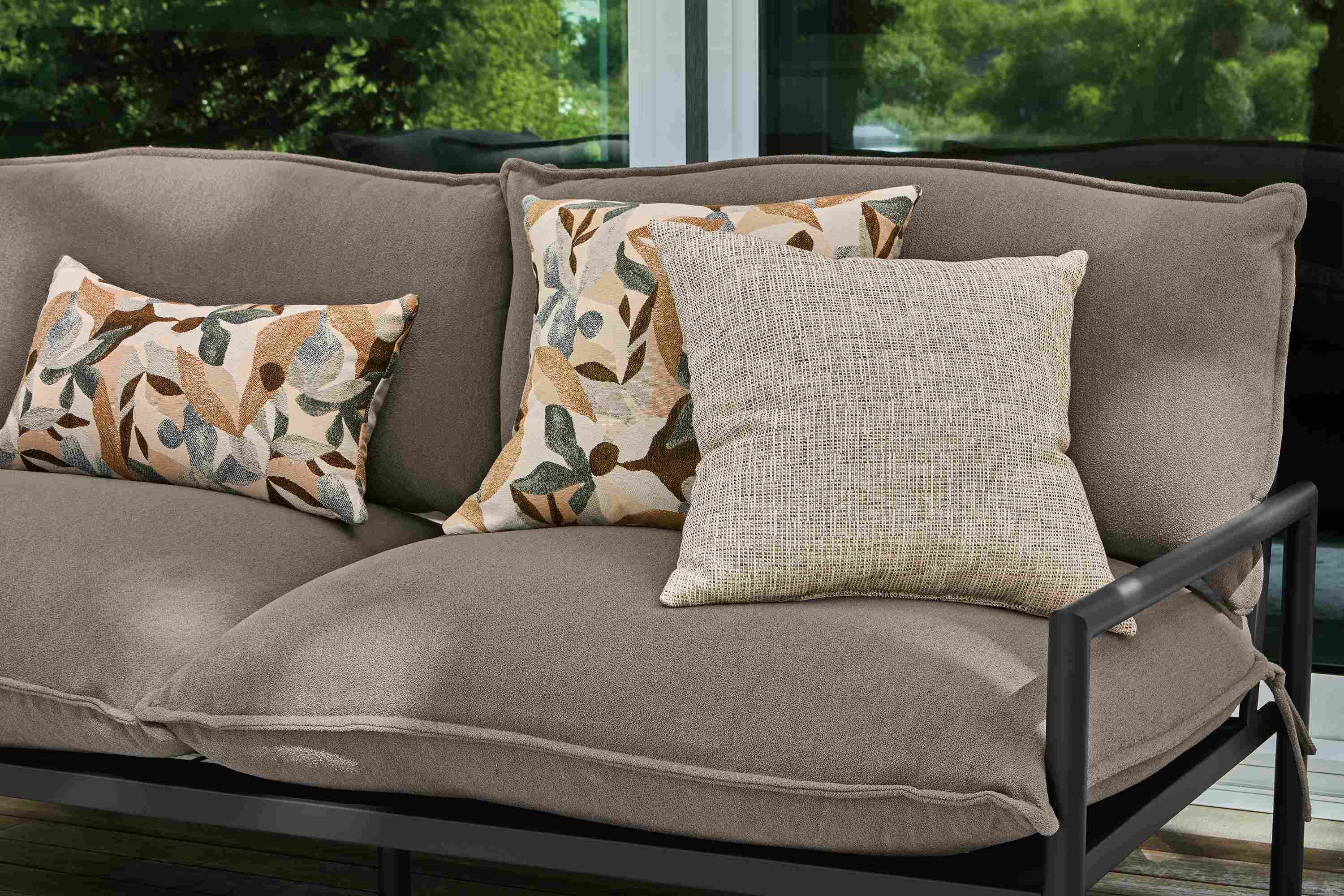 Detail of Izzy outdoor pillow in stone and Estes pillow in phipps taupe on a westbrook sofa in dusk putty.