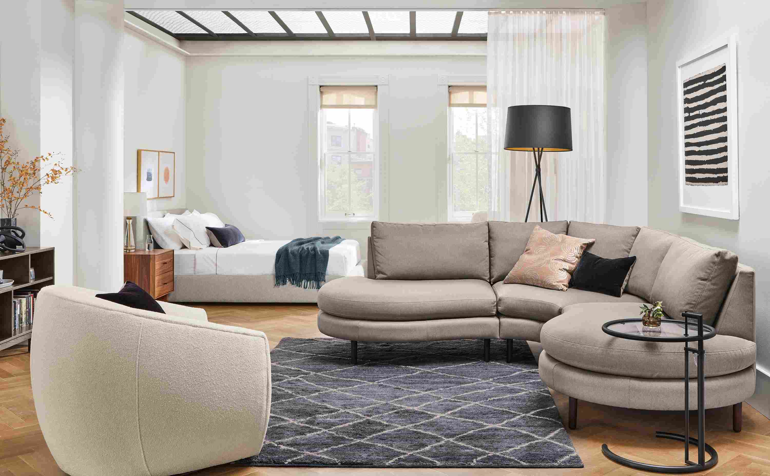 Living room with Jasper 3-piece curved sectional in Dawson cement and Mora swivel chair in Declan Ivory.