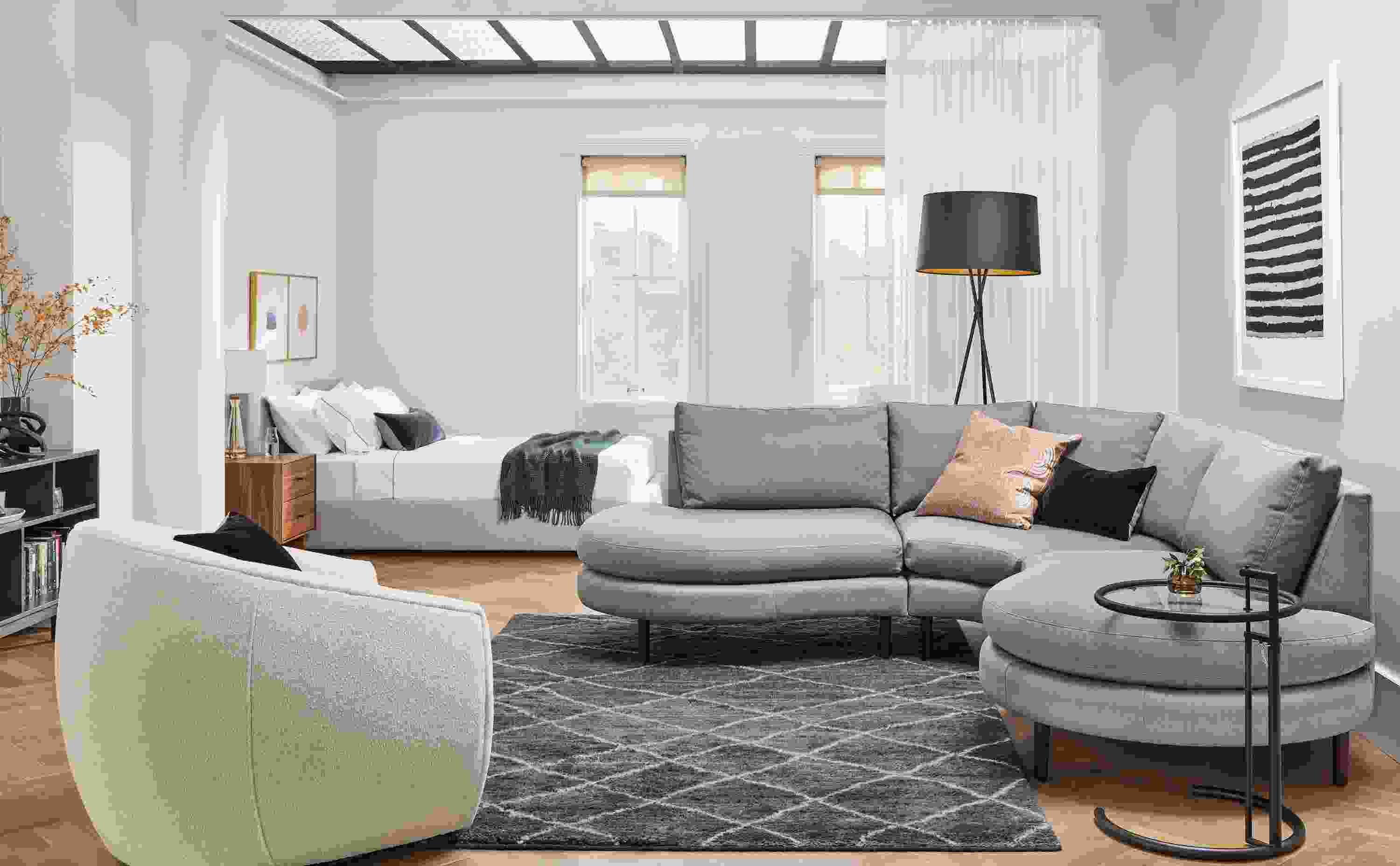 Living room with Jasper 3-piece curved sectional in Dawson cement and Mora swivel chair in Declan Ivory.