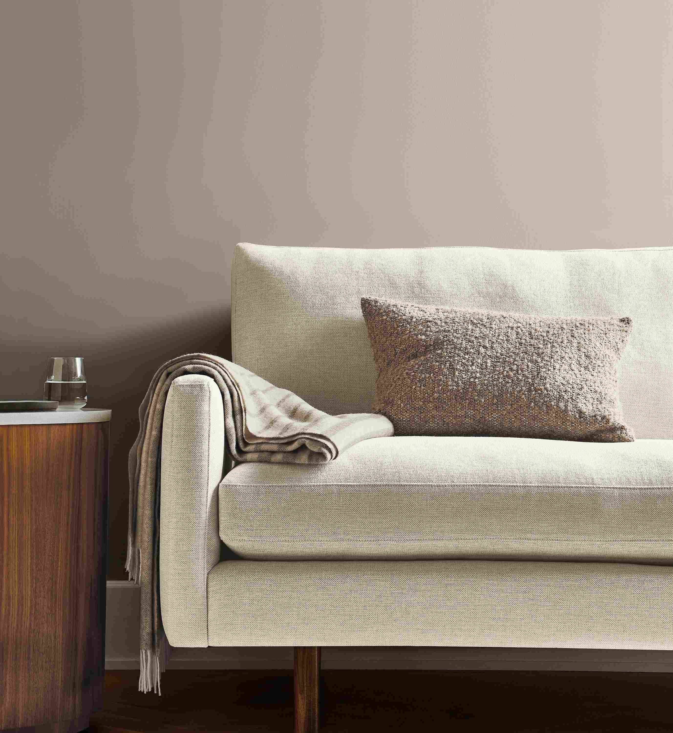 Front view of Jasper sofa in white fabric with Fairfax throw blanket and Palmer pillow in taupe.