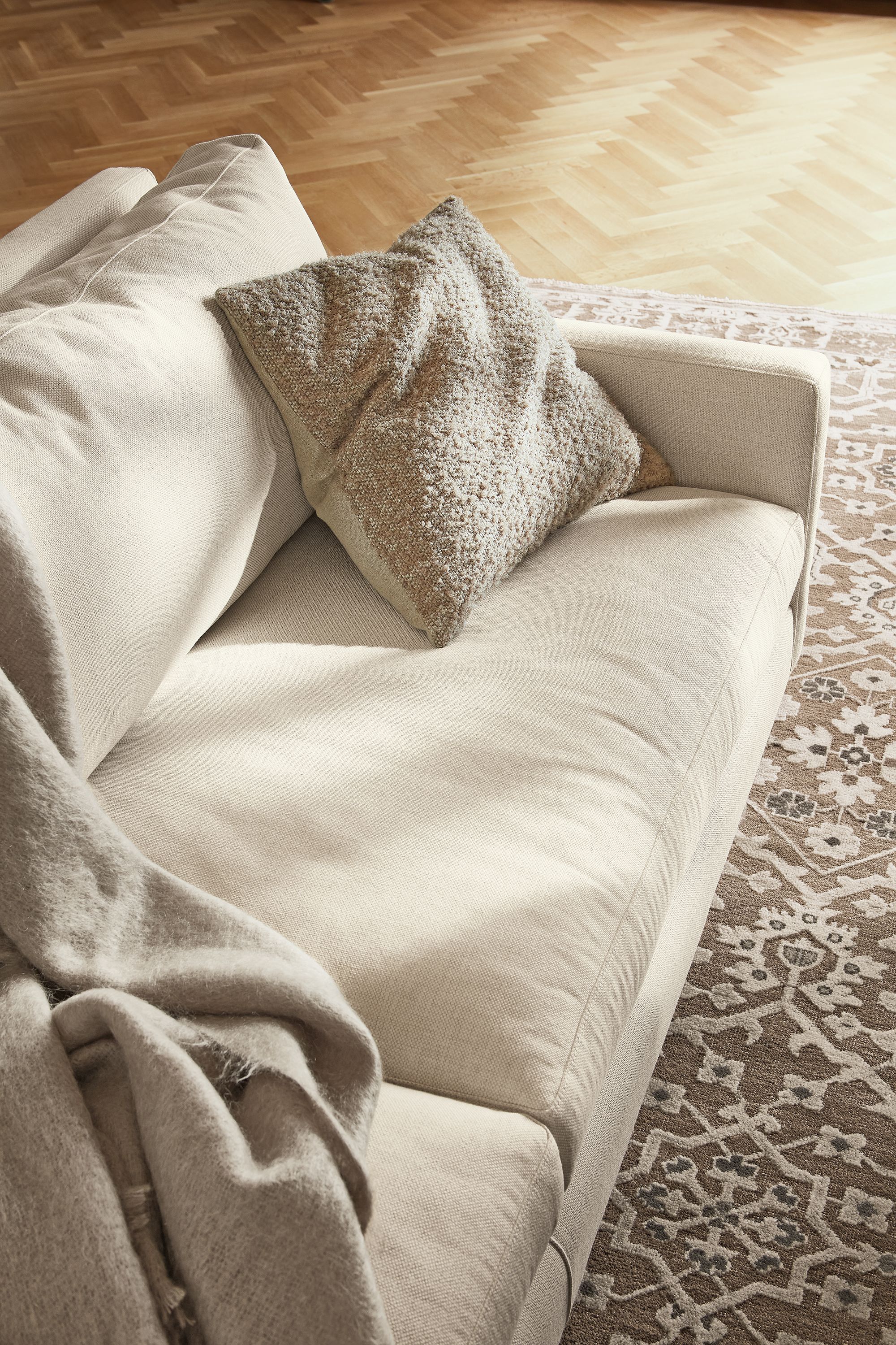 Close-up of Palmer throw pillow on Jasper sofa in Sumner Ivory.