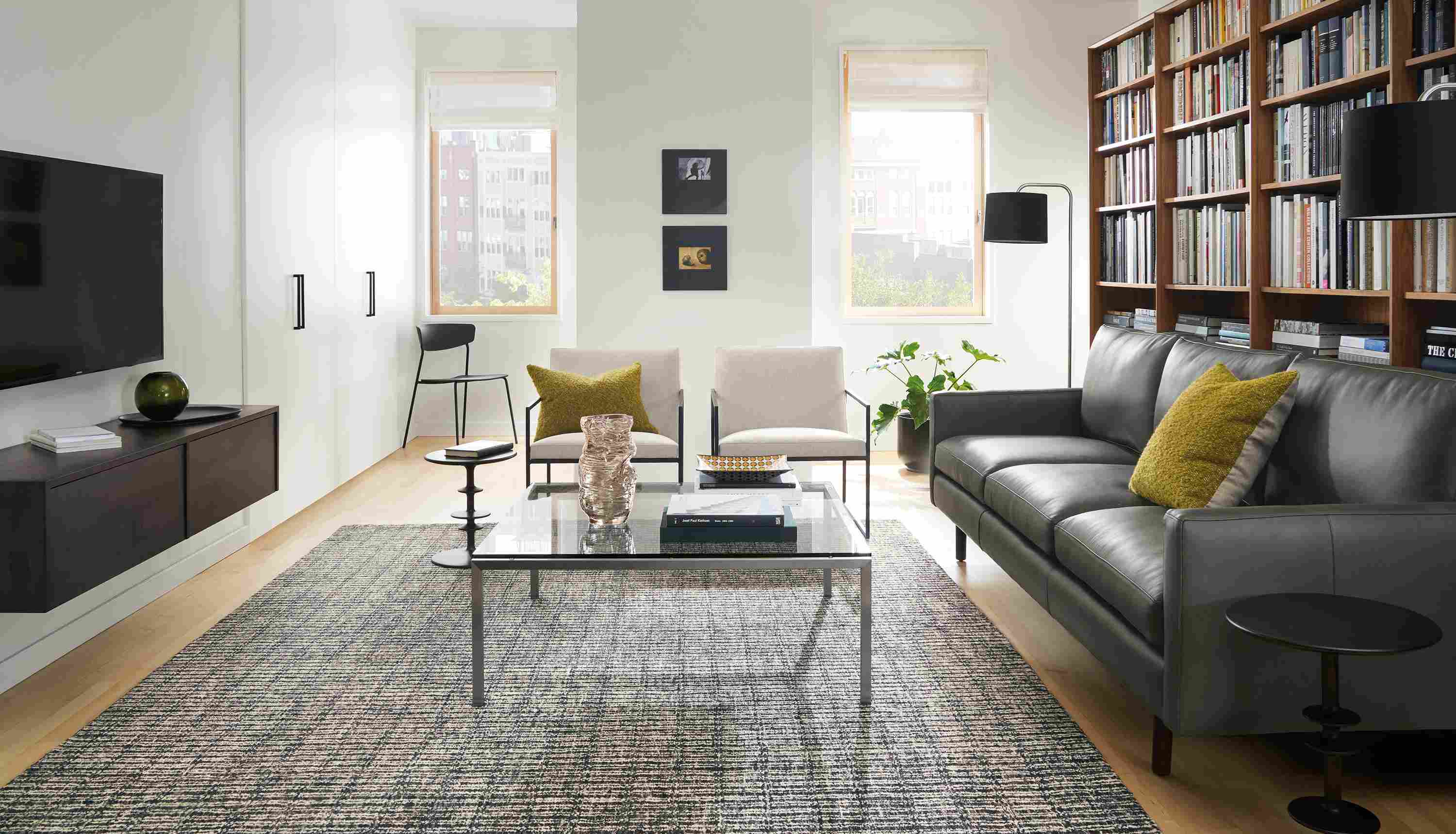 Living room with Jasper 96-wide sofa in Laino Slate leather, 2 Novato chairs in Flint Oatmeal and Nera rug in coal.