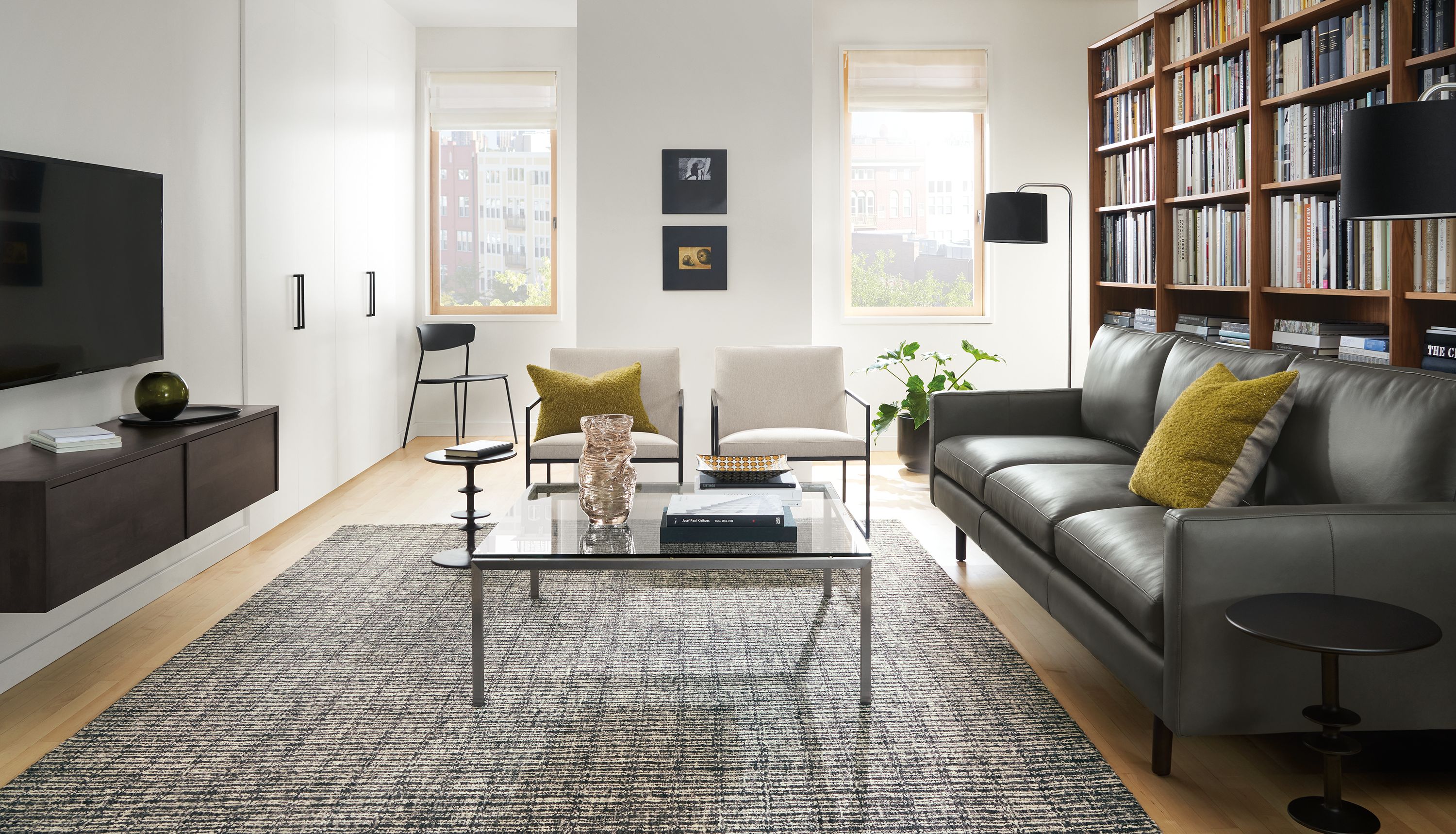 Living room with Jasper 96 wide three cushion sofa in Laino Slate leather, two Novato chairs in Flint Oatmeal and Nera rug in coal.