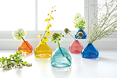 detail of jewel bud vases in various colors holding flowers displayed on counter.