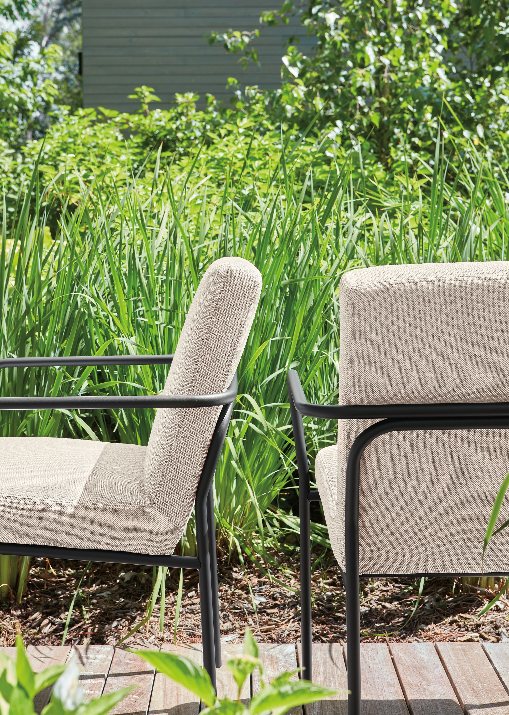 Detail of 2 Joel arm chairs in mist oatmeal and graphite on a deck.