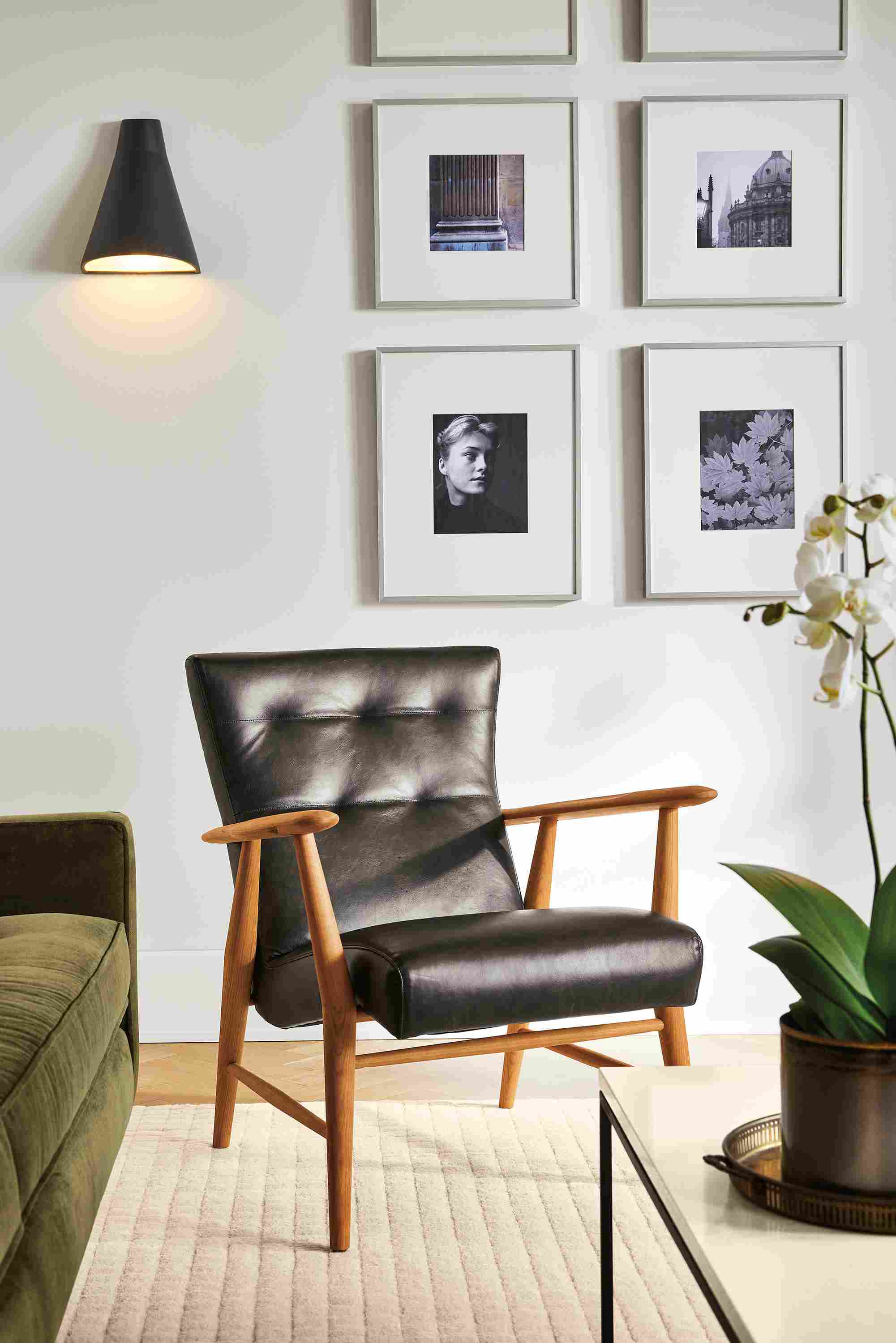Living room with Jonas lounge chair in Palermo charcoal leather and cherry wood and Vassan indoor wall sconce.