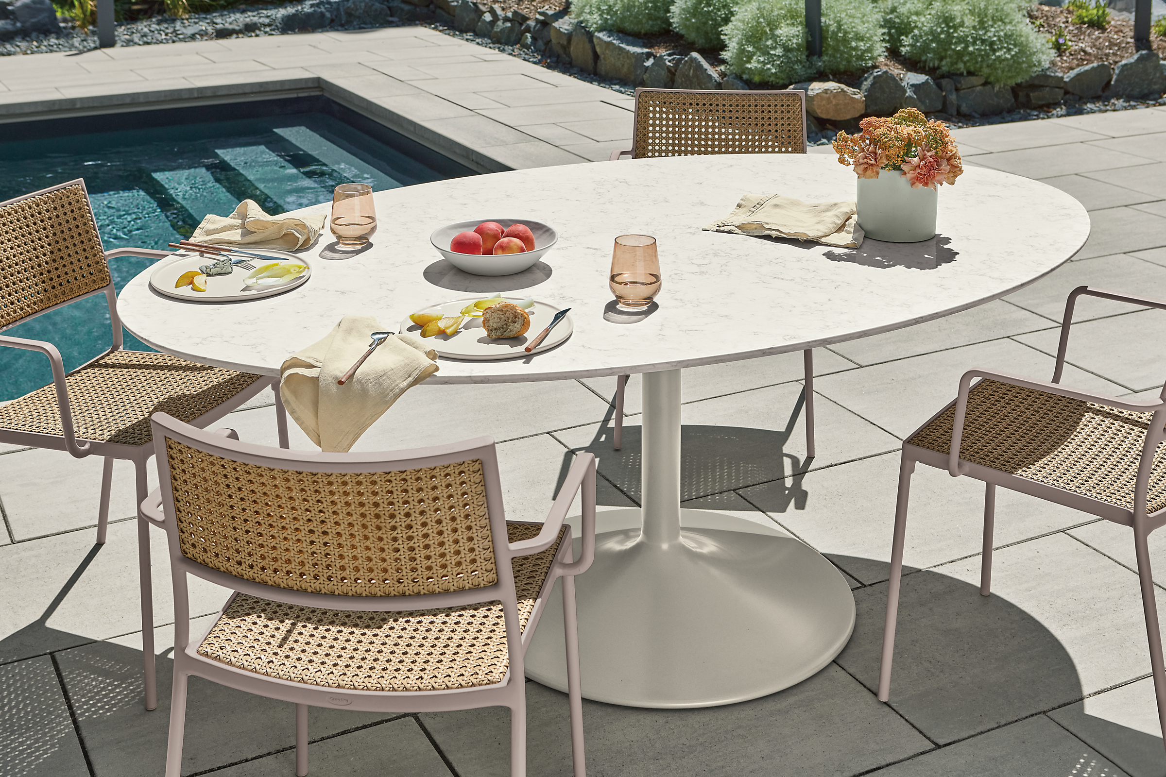 Julian outdoor oval table with four Plat chairs in natural with rose frame.
