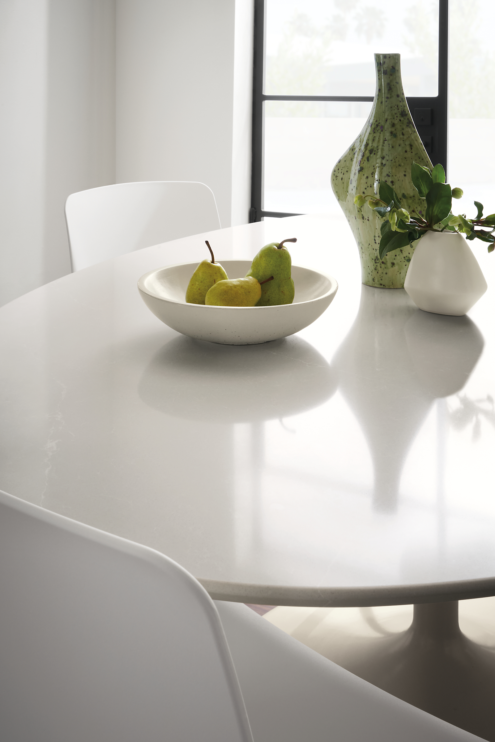 close-up of julian oval table in white with anya bowl and bud vase.
