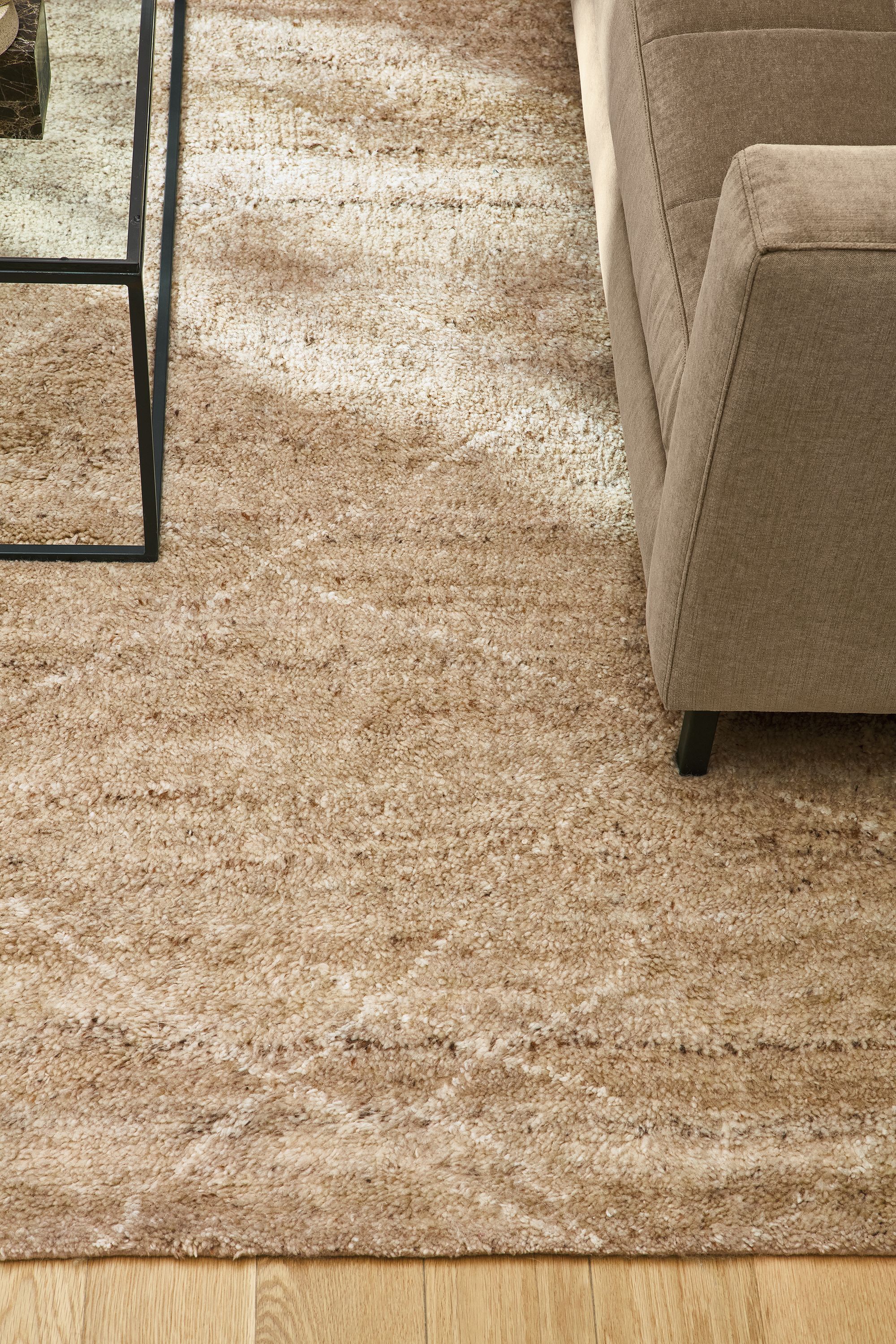 Living room with detail of Kalindi 8 by 10 rug in flax, Lloyd sofa in Windsor Otter and Tyne coffee table with clear glass.