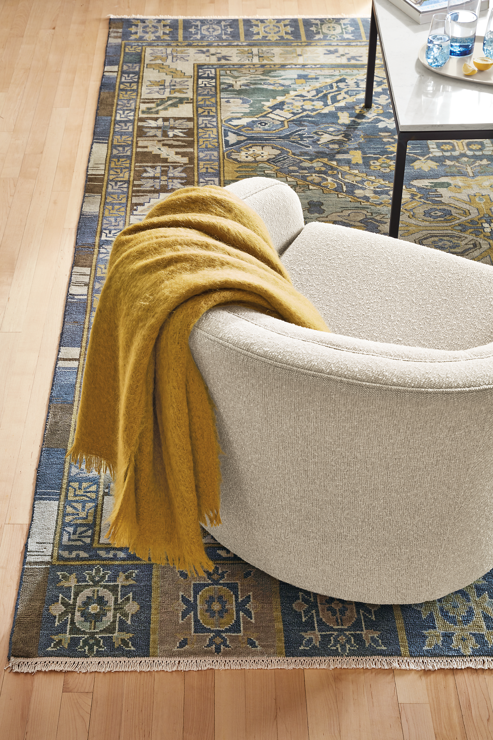 detail of townes throw blanket draped over amos swivel chair on kayseri rug.