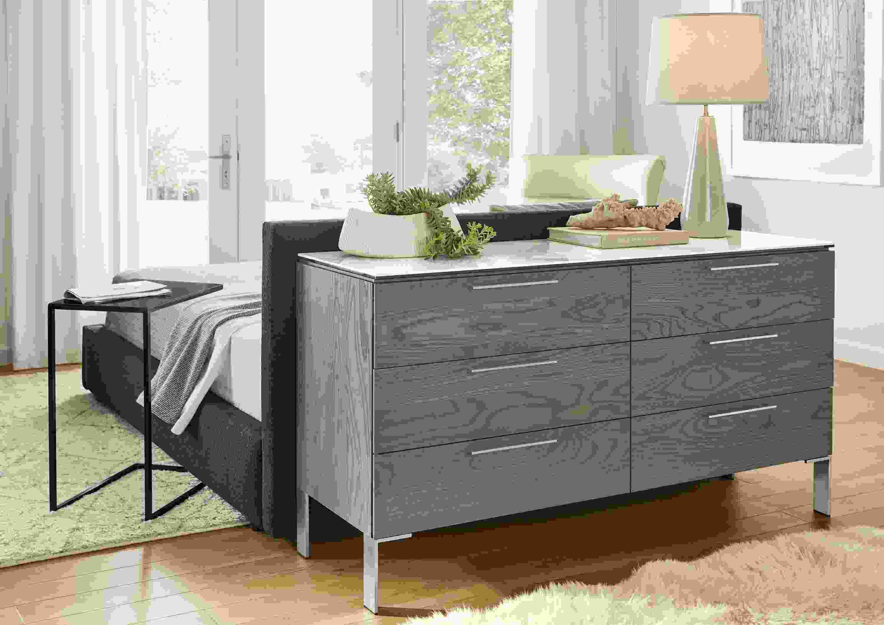 Detail of Kenwood dresser in ash with shell stain and ceramic top behind bed in bedroom.