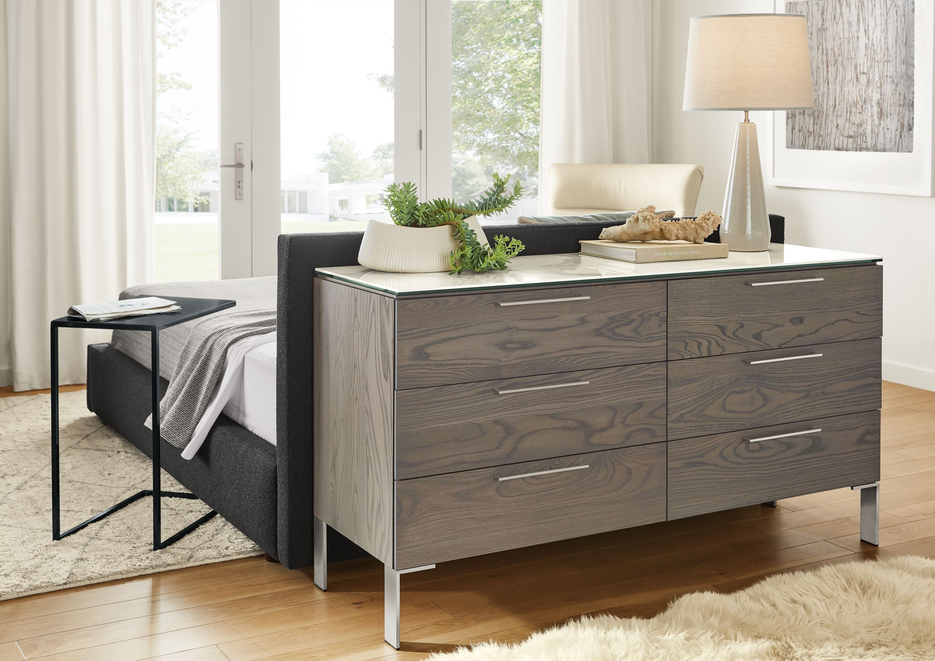 Detail of Kenwood dresser in ash with shell stain and ceramic top behind bed in bedroom.