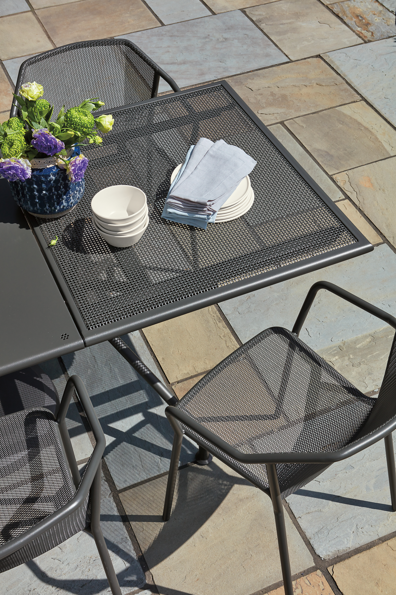 Top down detail of Kona outdoor extension table with 20-inch leaf and theo chairs in graphite.