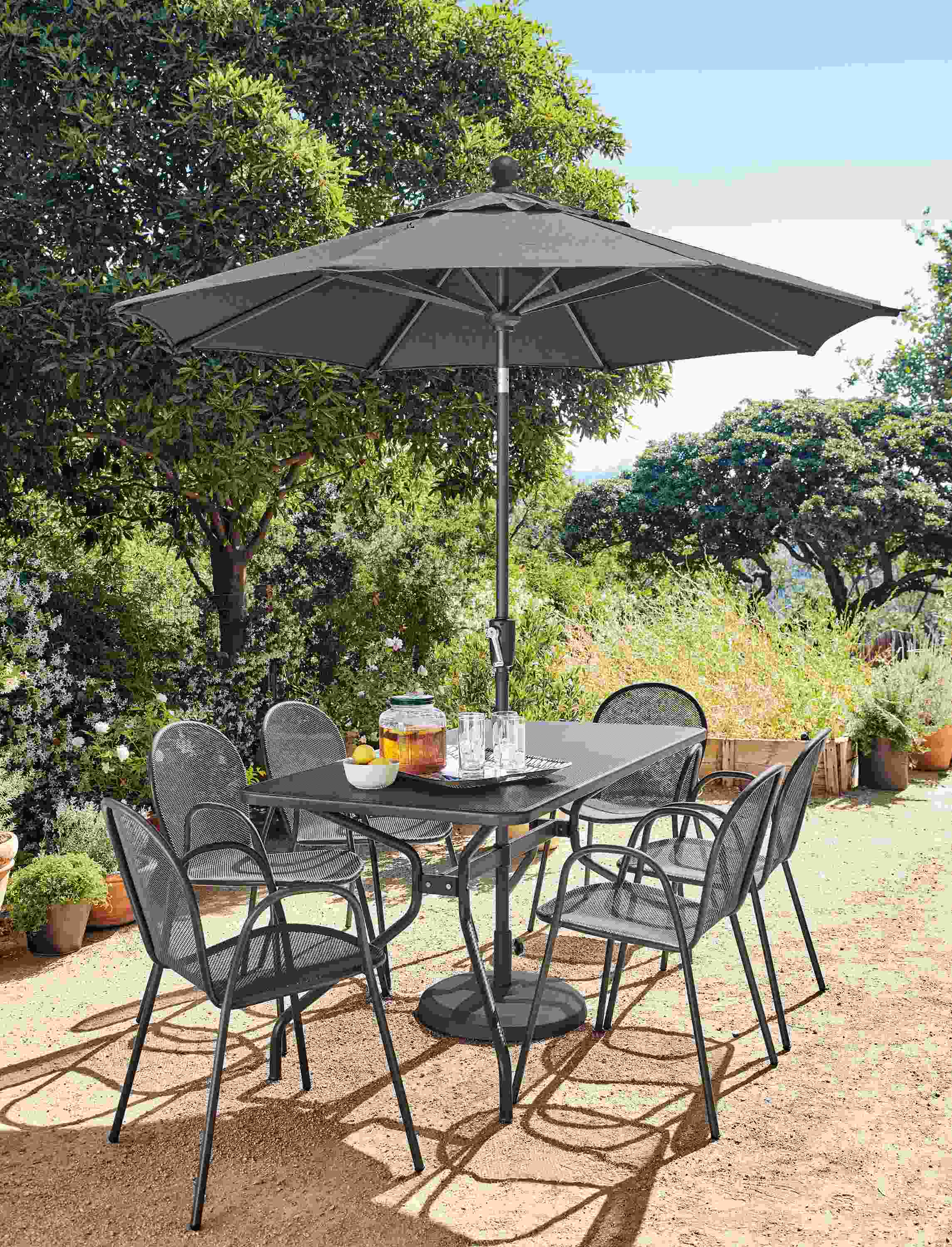 Patio with Kona table in graphite and 6 Rio chairs in graphite and Maui umbrella in tavros charcoal.