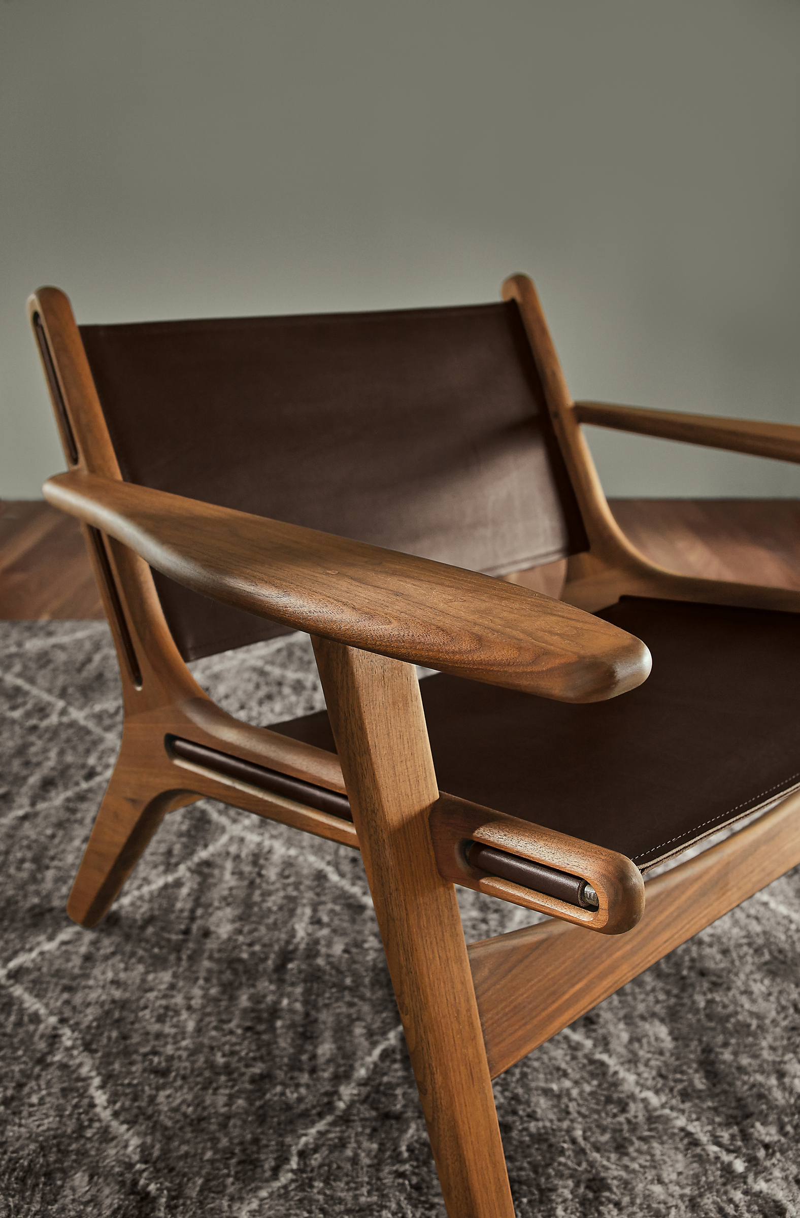 close-up of lars lounge chair in walnut and sellare smoke leather, set on kalindi rug in charcoal.