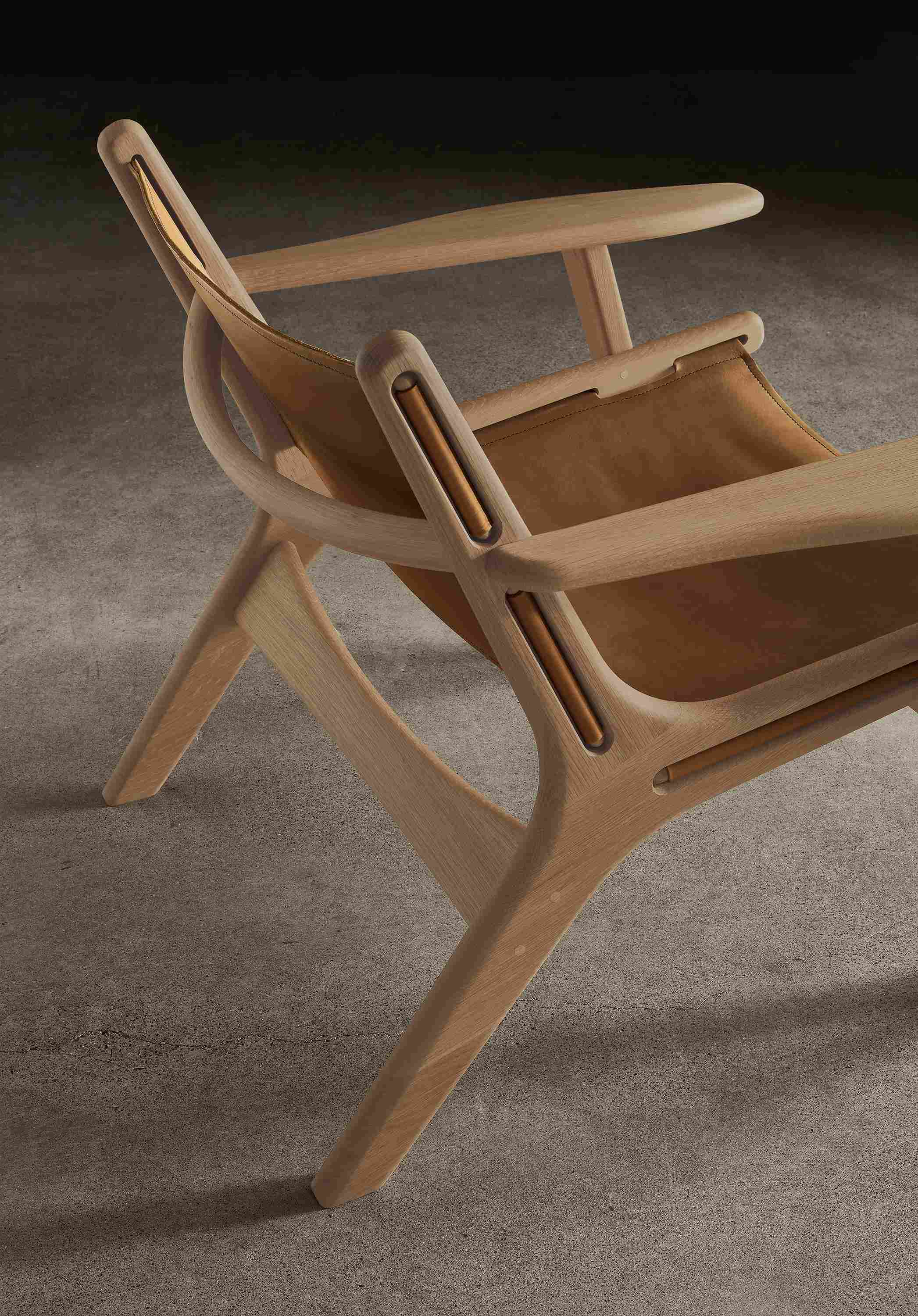 View of a Lars lounge chair in rye on red oak with sellare cognac leather showing the back and corner.
