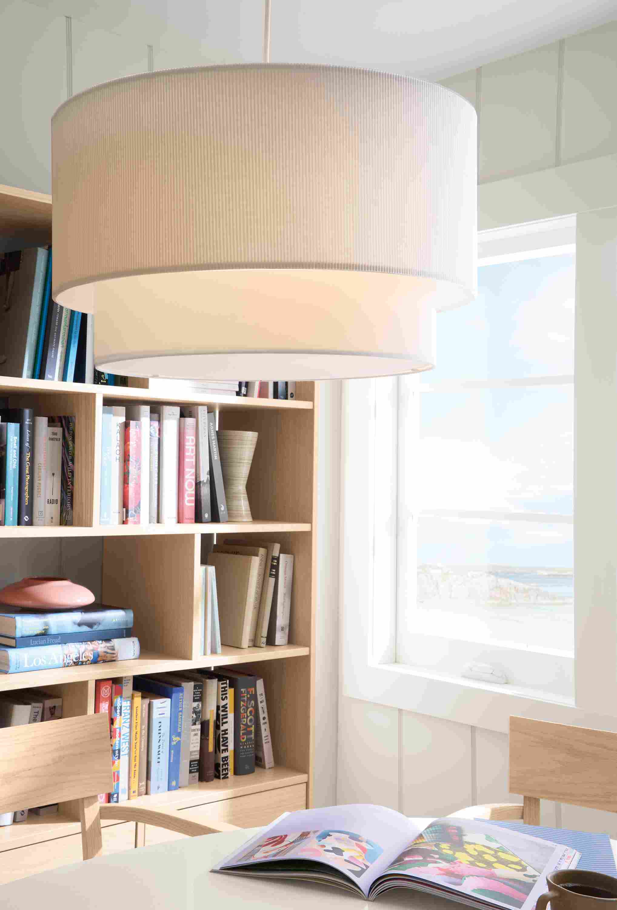 Detail of a Leighton Pendant light with pleated white shade above an Aria oval table with white quartz top in a dining room.