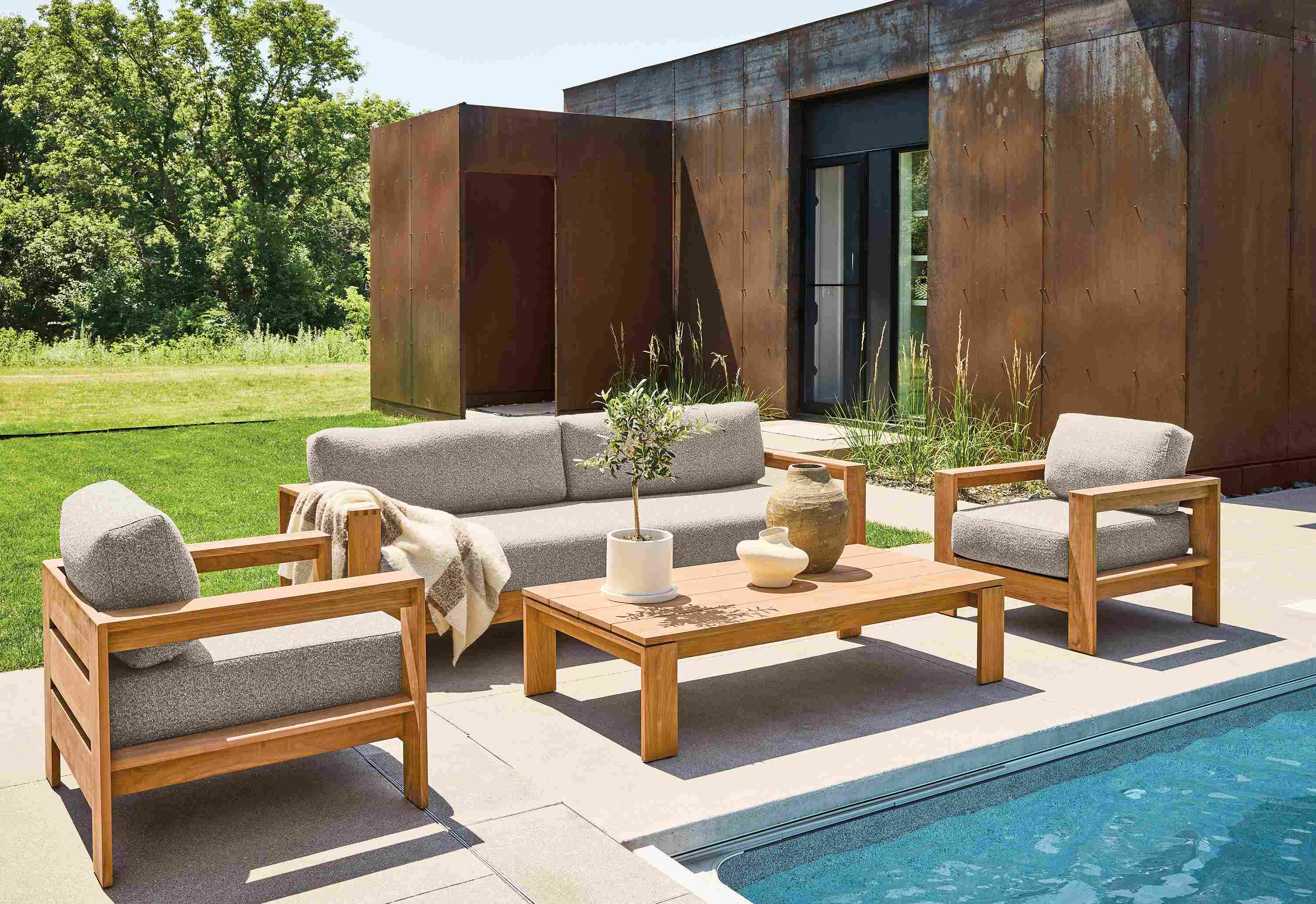 Poolside seating area with Leti sofa, lounge chairs and coffee table in teak heartwood and Kloss Otter.