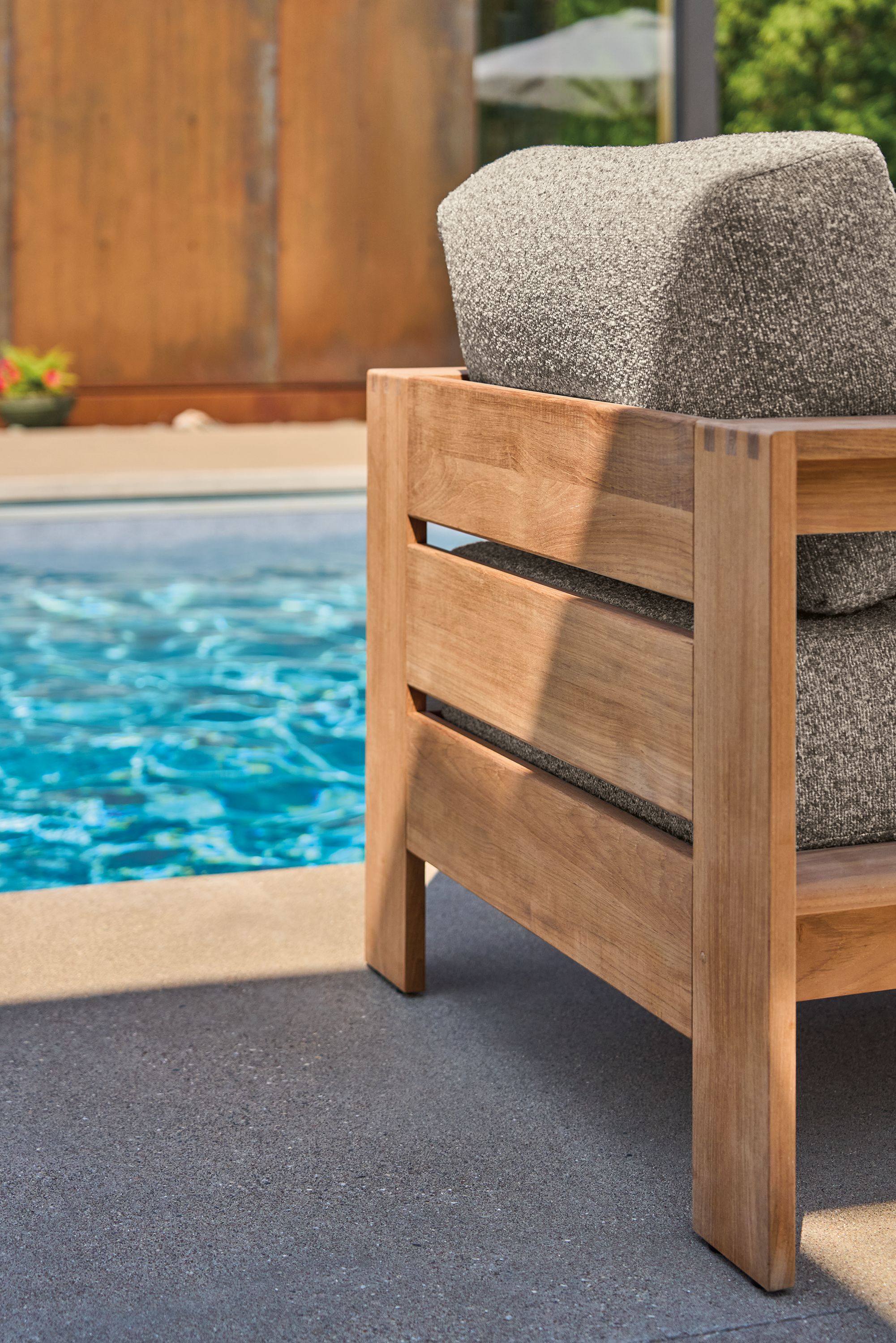 Poolside detail of backside of Leti Lounge chair in teak heartwood with Kloss Otter fabric.