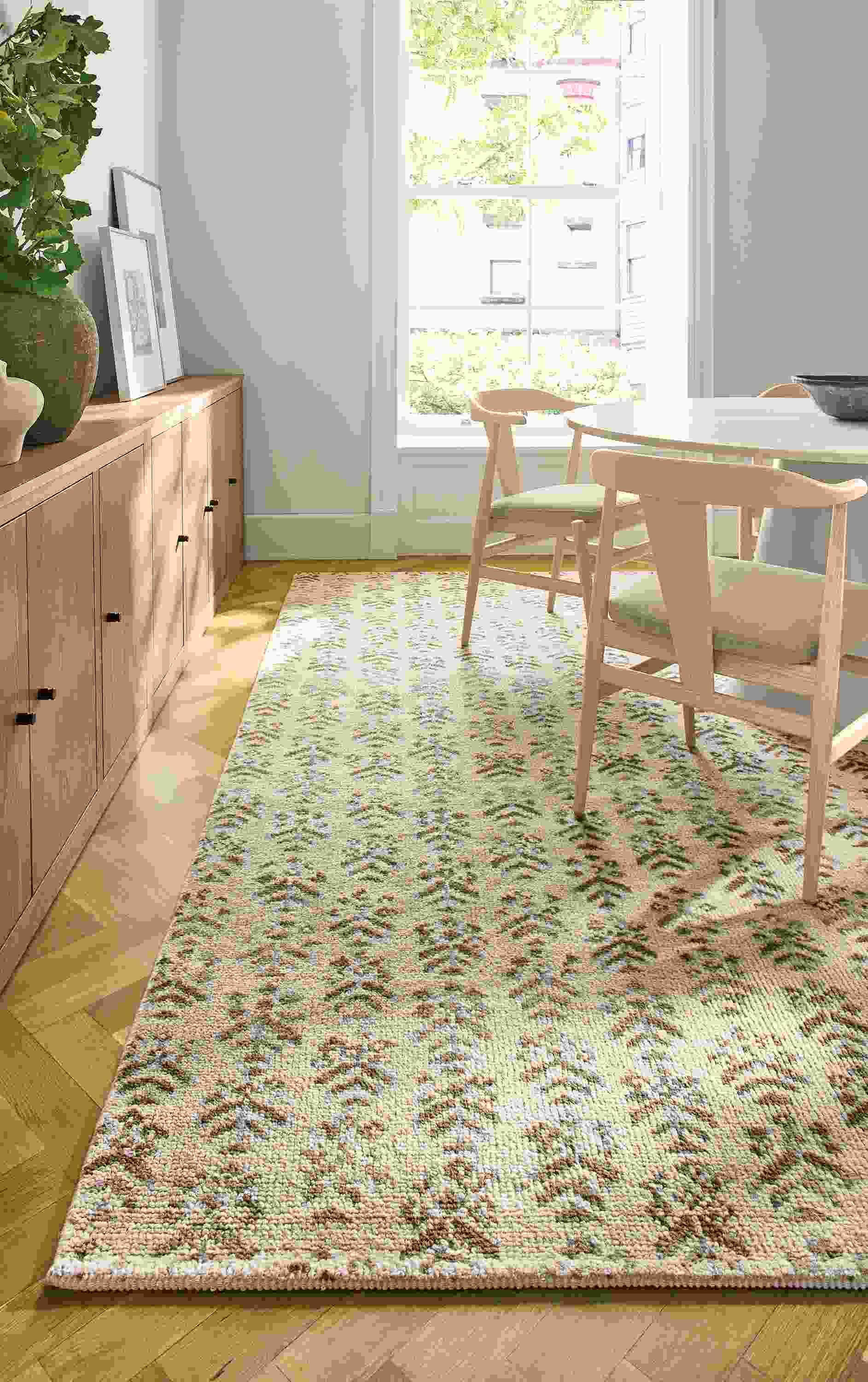 Dining room with Leyla 8 by 10 rug in snow and Decker round table in taupe with marbled warm white quartz top.