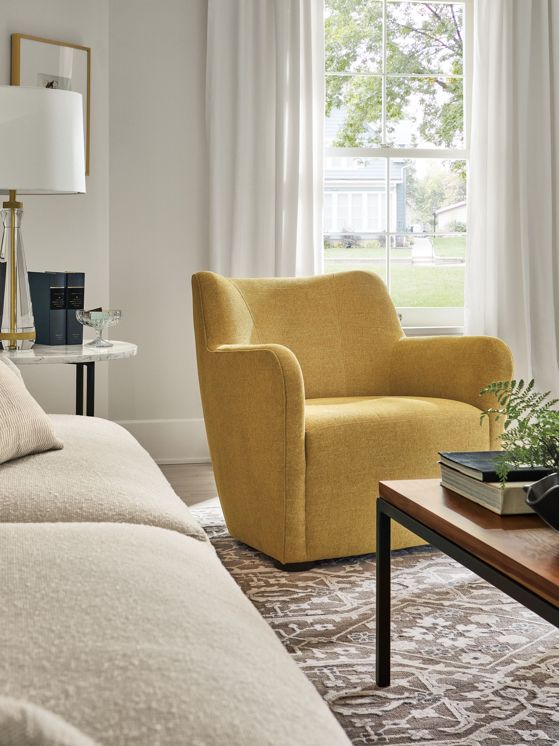 living room with lily chair in hawkins mustard fabric, vanya rug, parsons coffee table, gatsby table lamp.