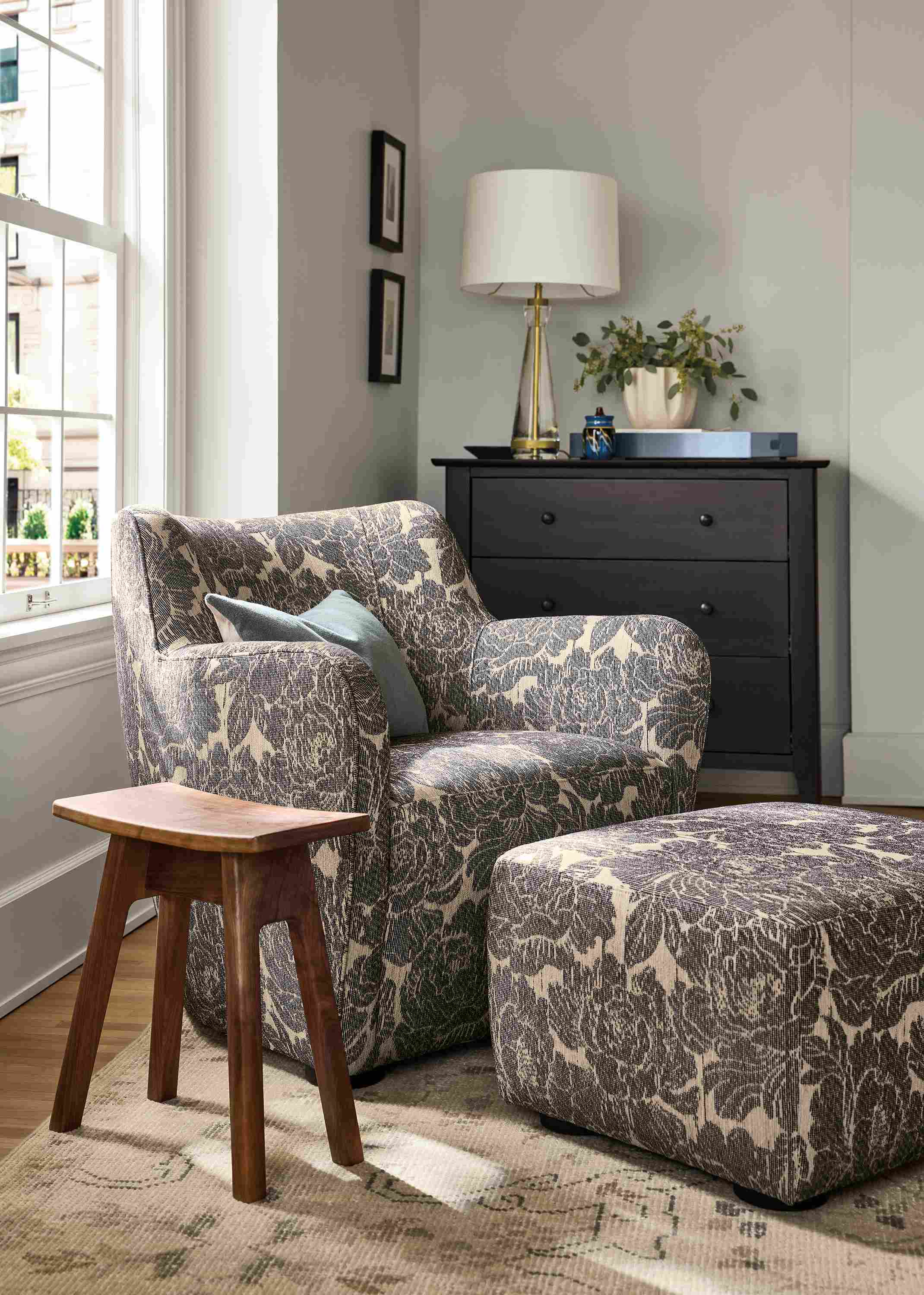 Room with detail of Lily chair and ottoman in Caldwell Navy and Hanneman curve-top stool in reclaimed walnut.