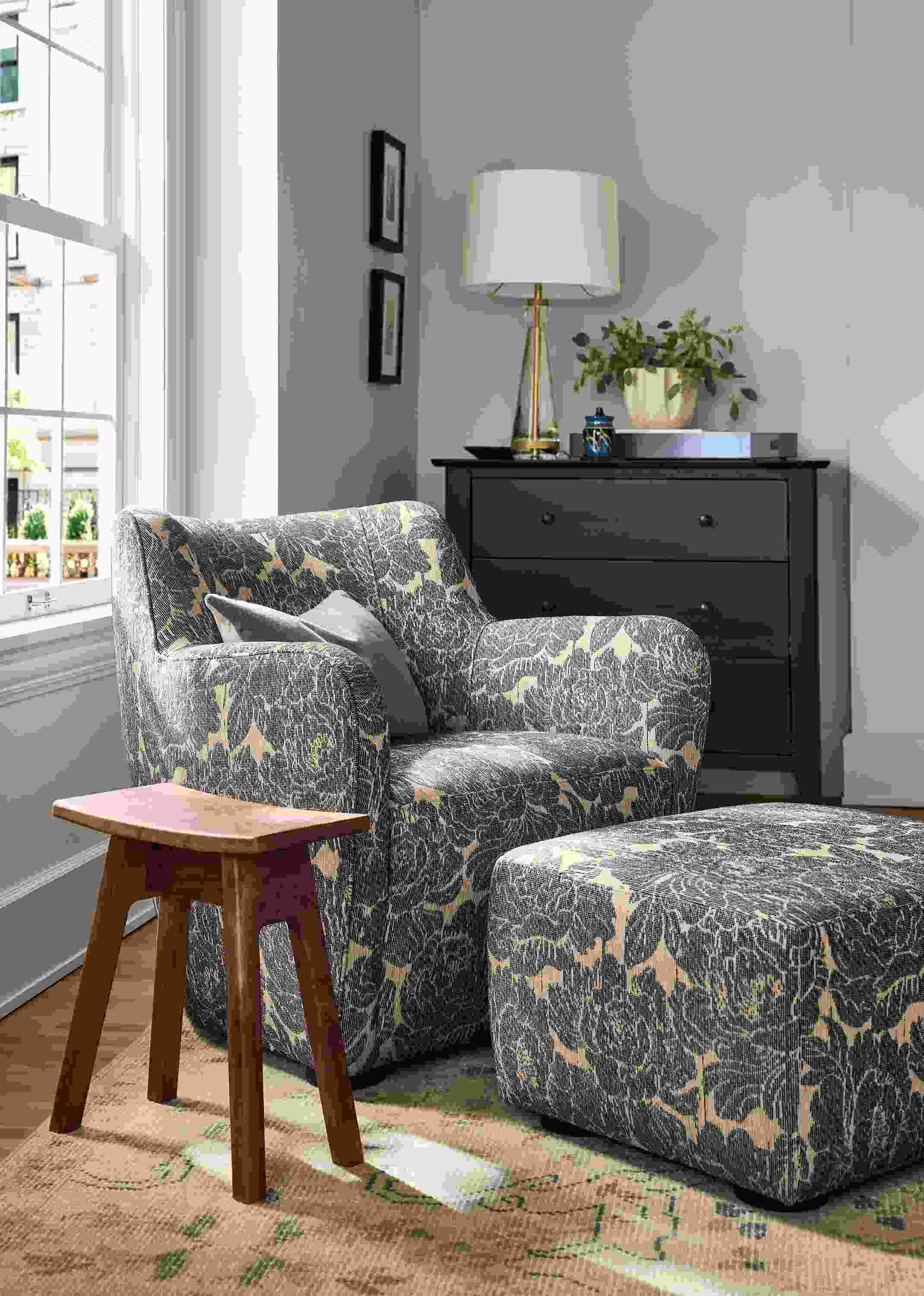 Room with detail of Lily chair and ottoman in Caldwell Navy and Hanneman curve-top stool in reclaimed walnut.