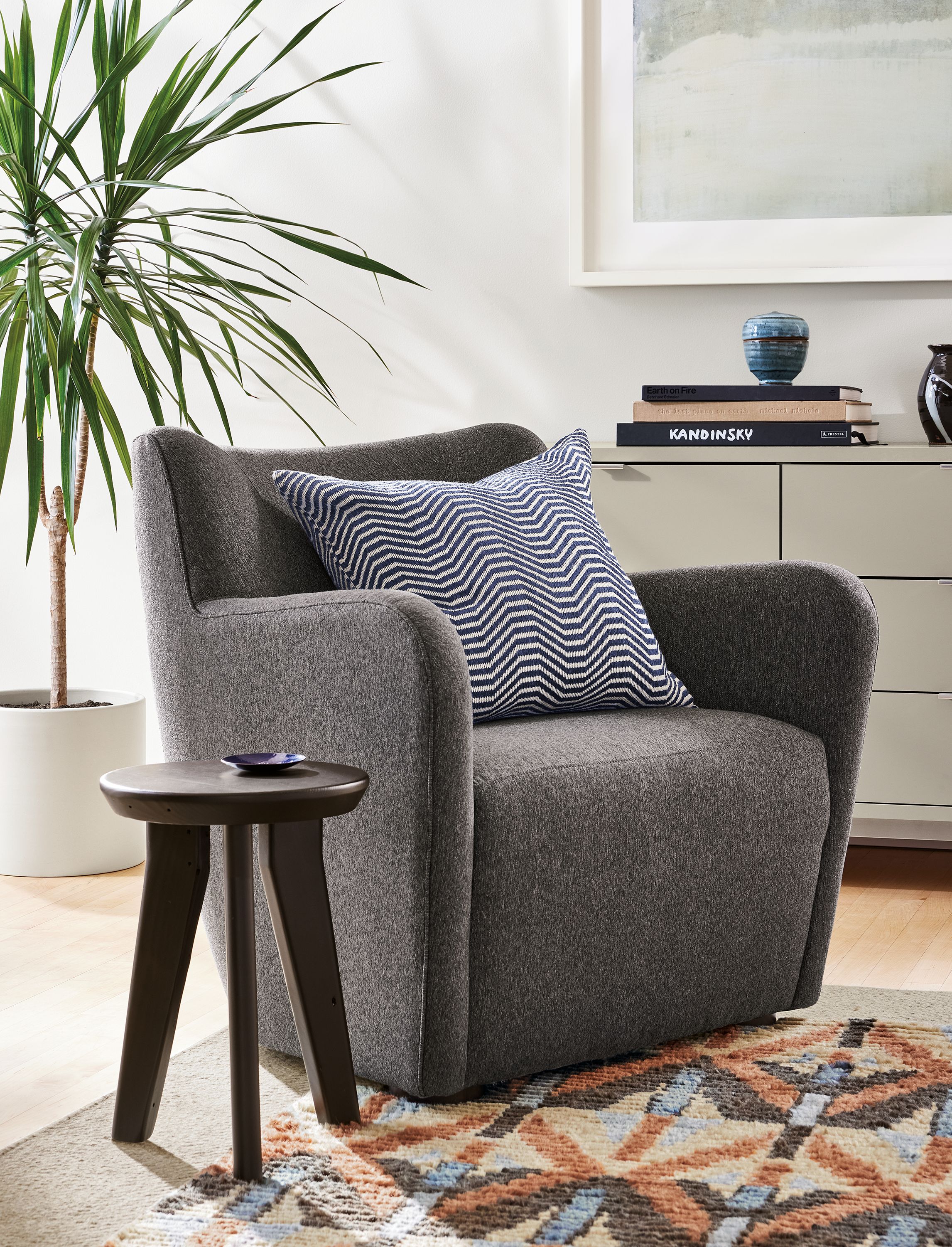 living room with lily chair in flint gunmetal fabric, hollins stool, avilia rug.