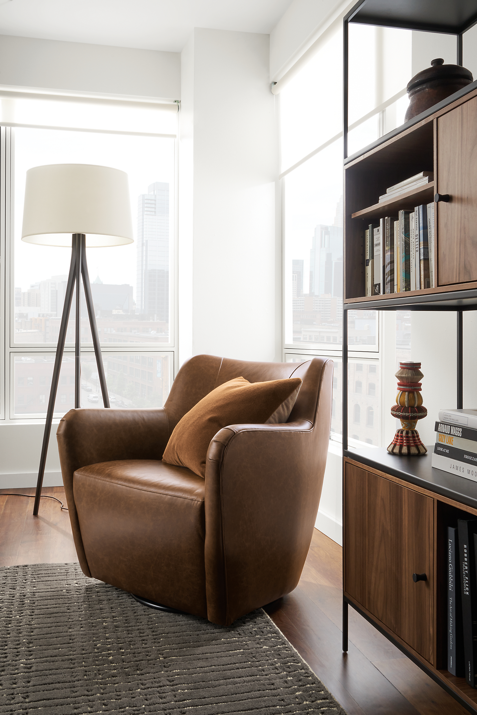 Living room with Lily swivel chair in bourbon leather and slim 42-wide by 72-high bookcase with walnut insertts.