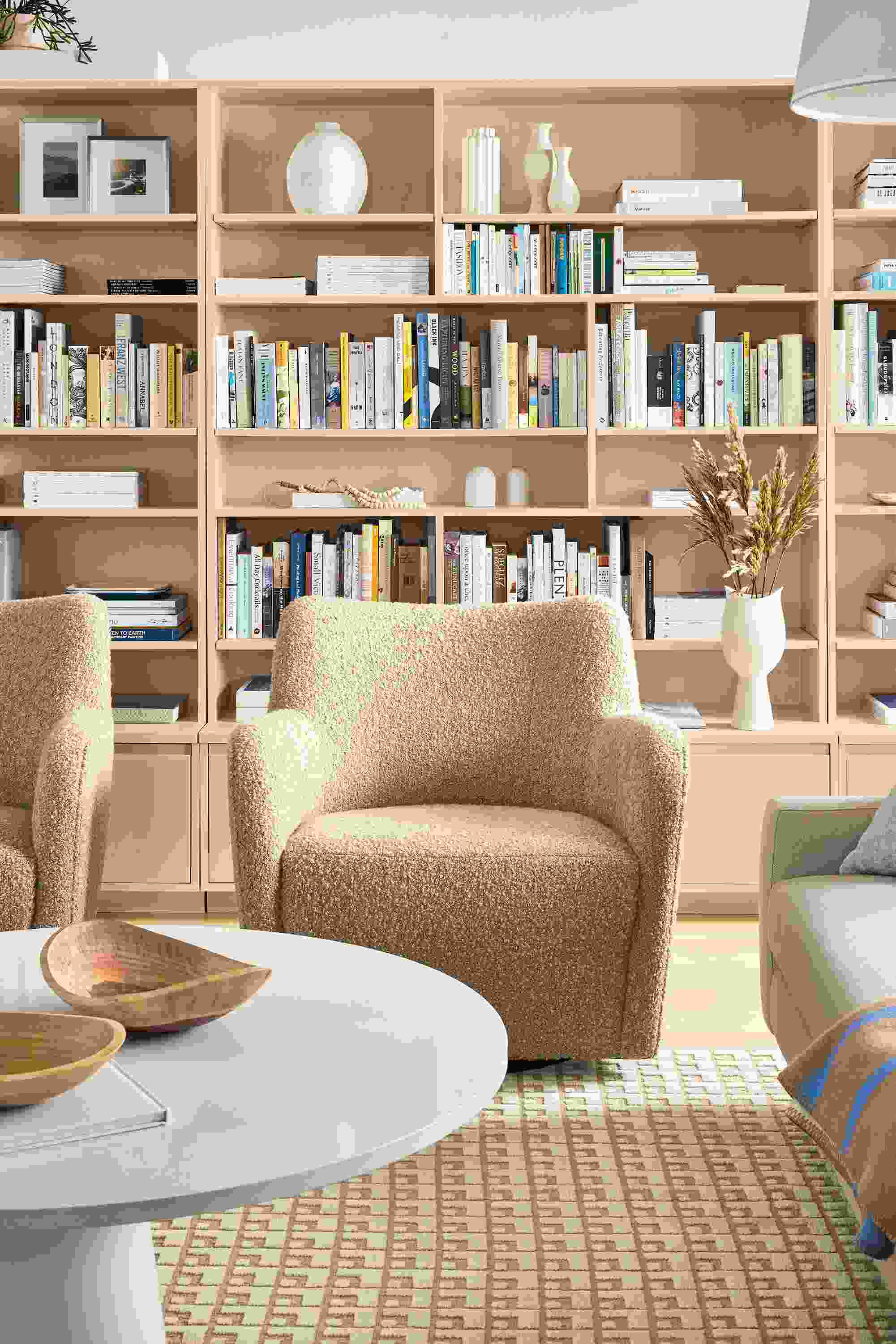 Living room with two lily swivel chairs in dornick  camel fabric and decker round en table in white with white quartz top.