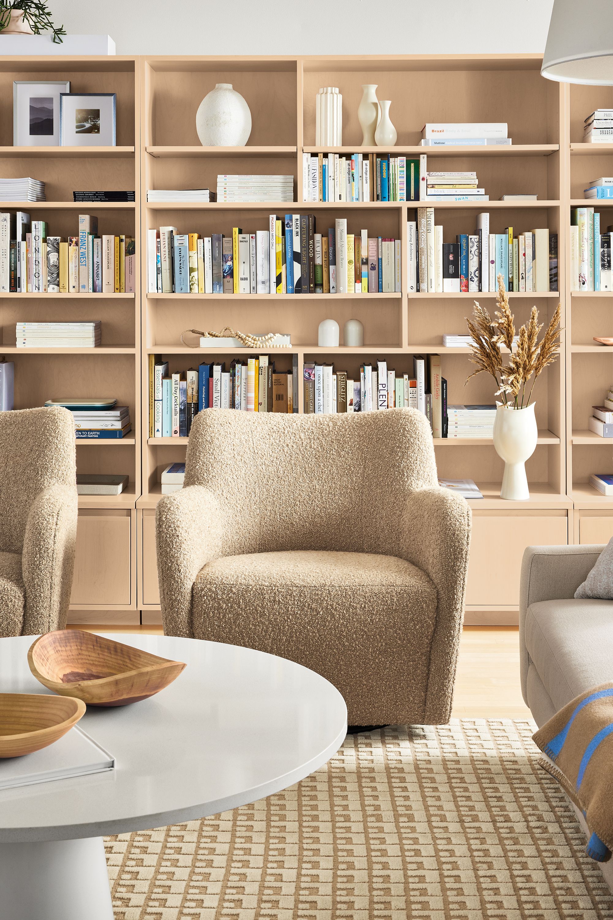 Living room with two lily swivel chairs in dornick  camel fabric and decker round en table in white with white quartz top.