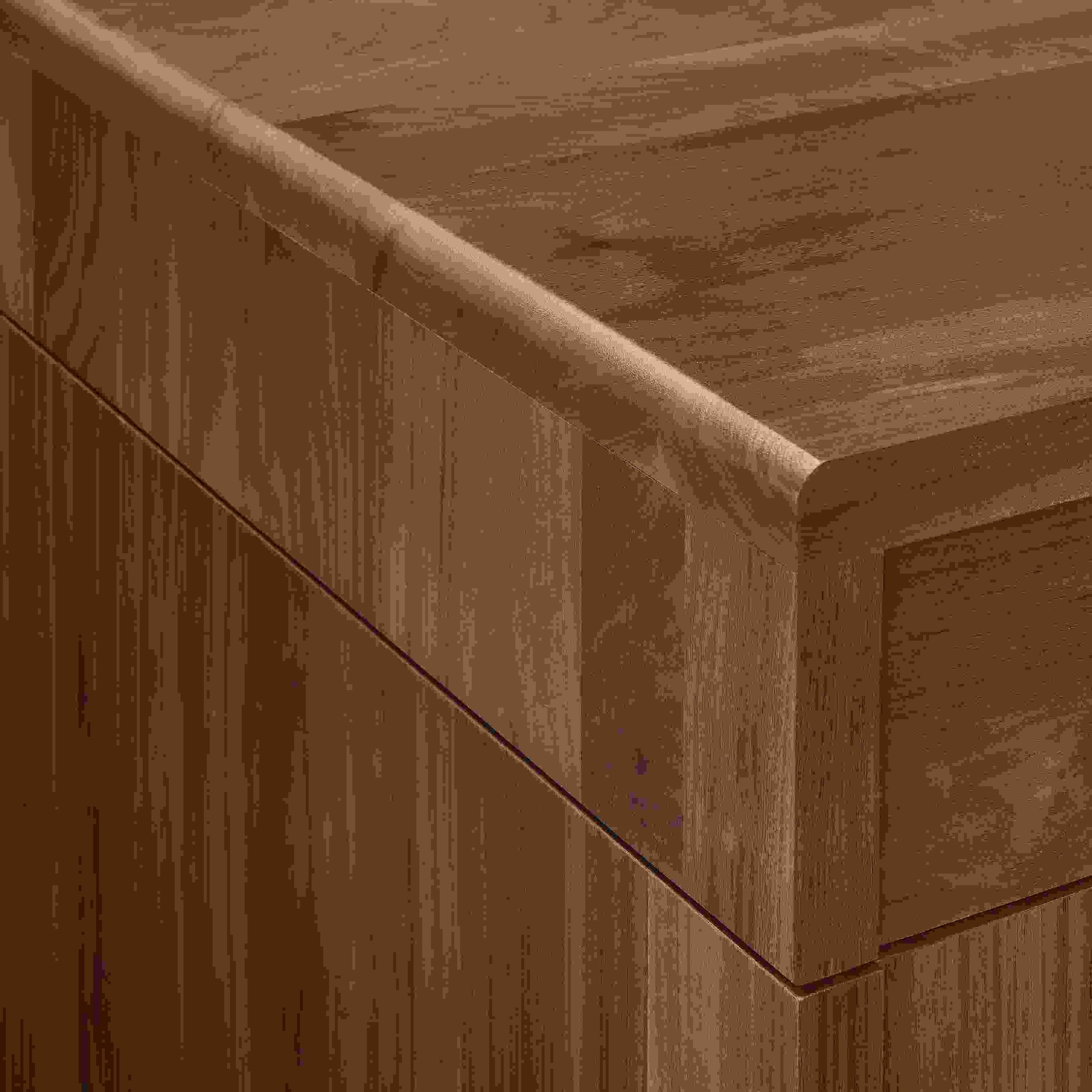 Detail of Lincoln adjustable standing desk in walnut showing corner of desk and seam where top and base meet.