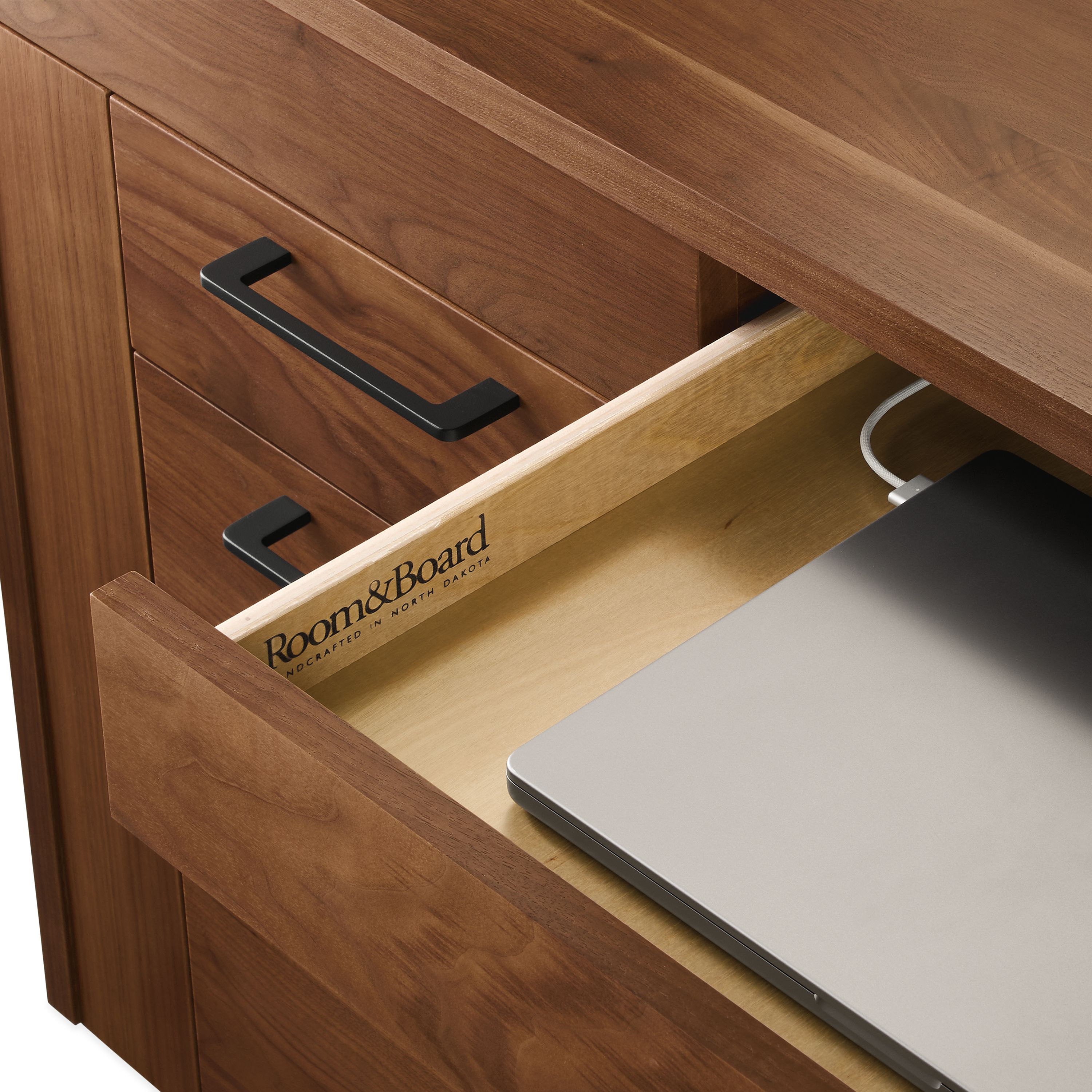 Detail of open drawer with a plugged in laptop on a Lincoln 72-wide adjustable standing desk in walnut.