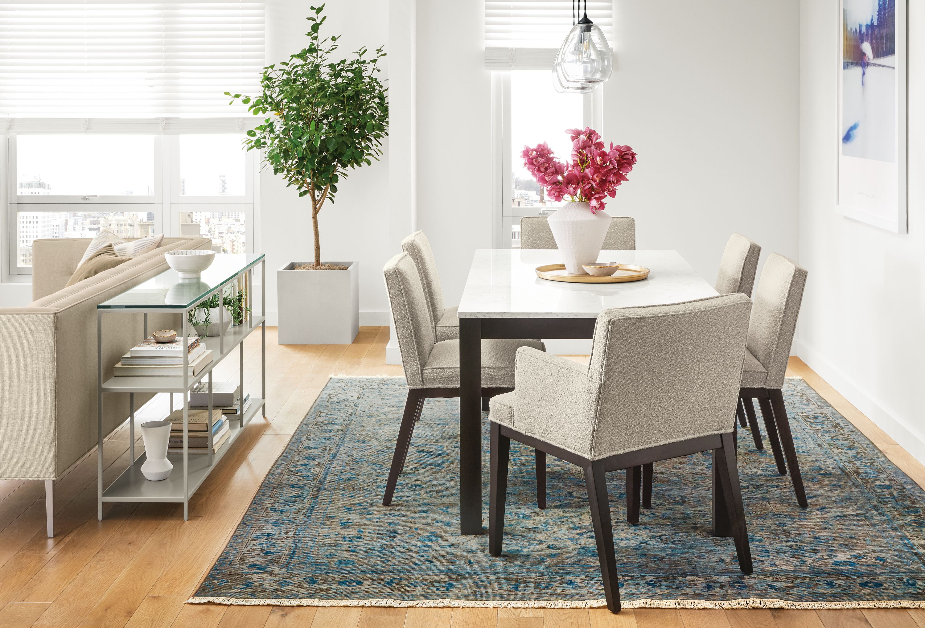 Detail of Linden dining table with marbled white quartz top in dining space with blue rug.