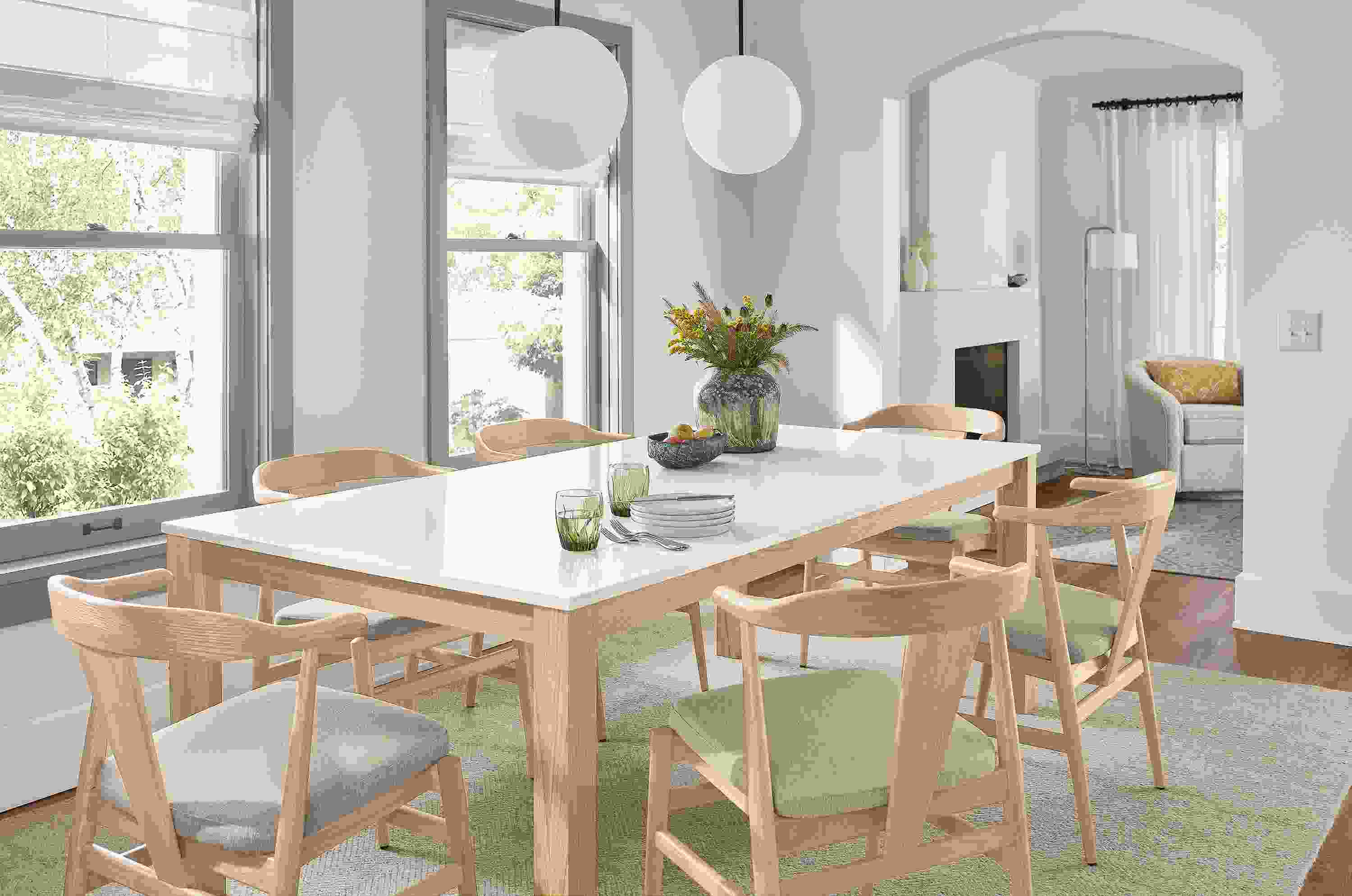 Dining room with linden table with white quartz top and salt on red oak base, 6 evan chairs in salt on red oak and two orbit pendants.
