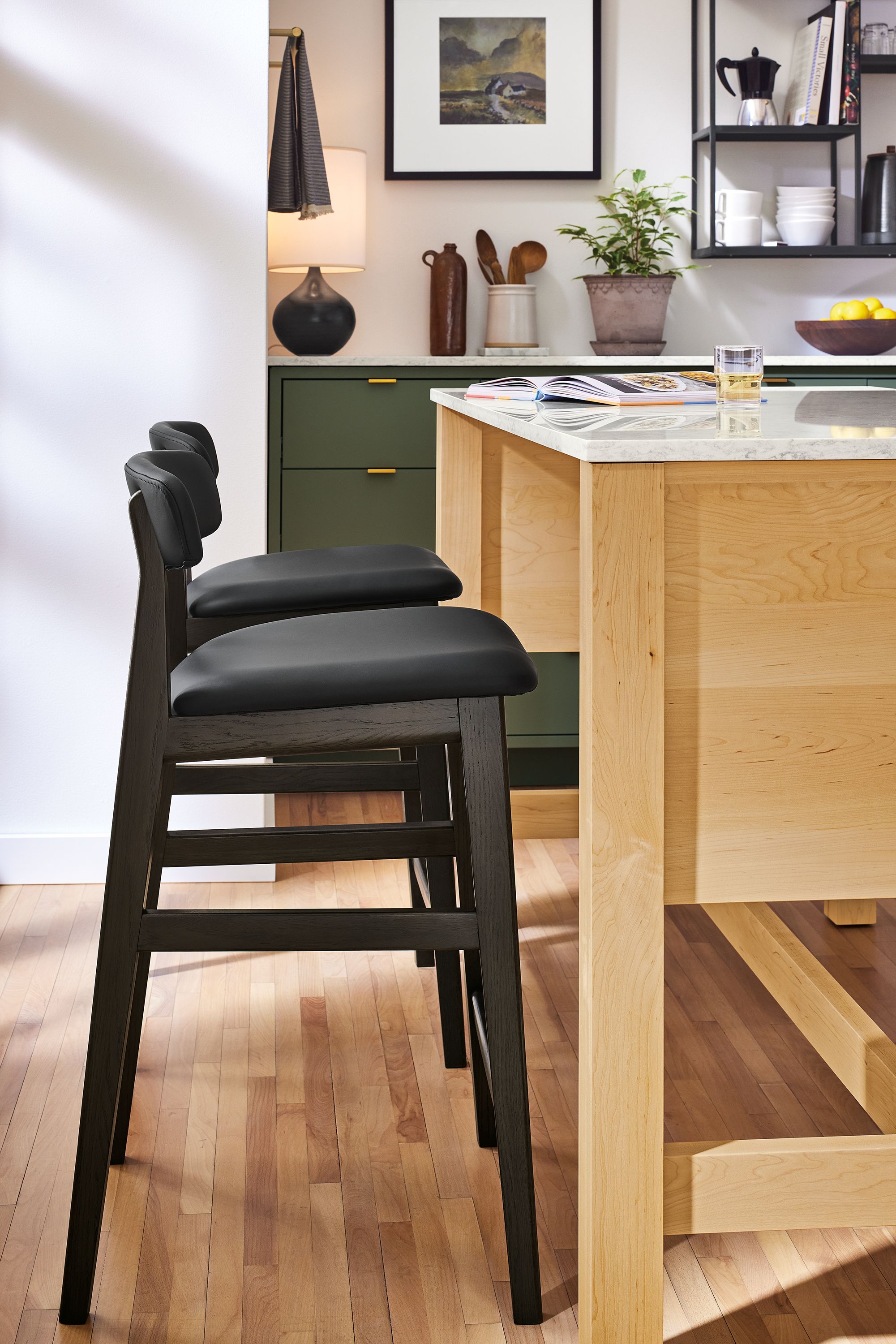 Kitchen with 2 Errol Counter Stools in Buri Black leather and Errol kitchen island in maple and marbled white quartz.