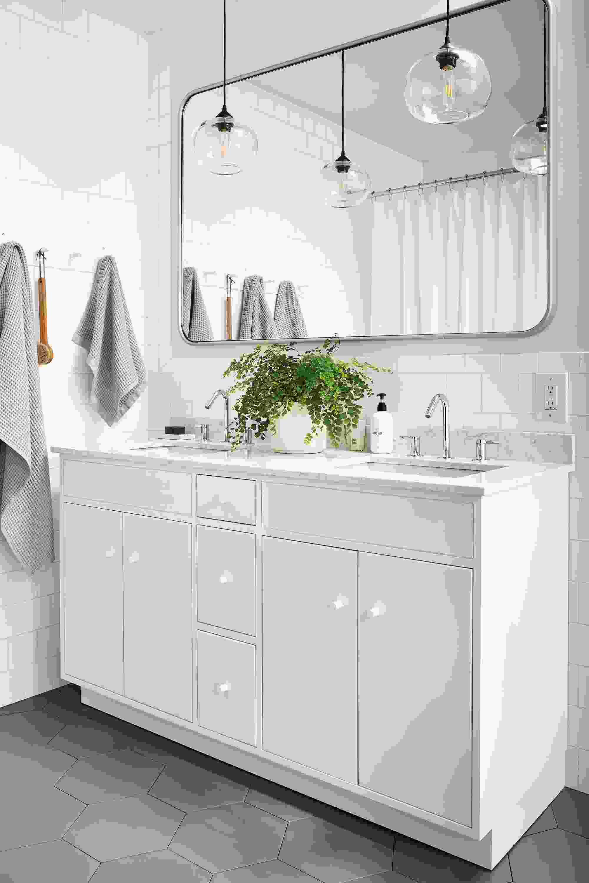 bathroom with linear vanity in white with marbled white quartz top, lyndale mirror, sky pendants