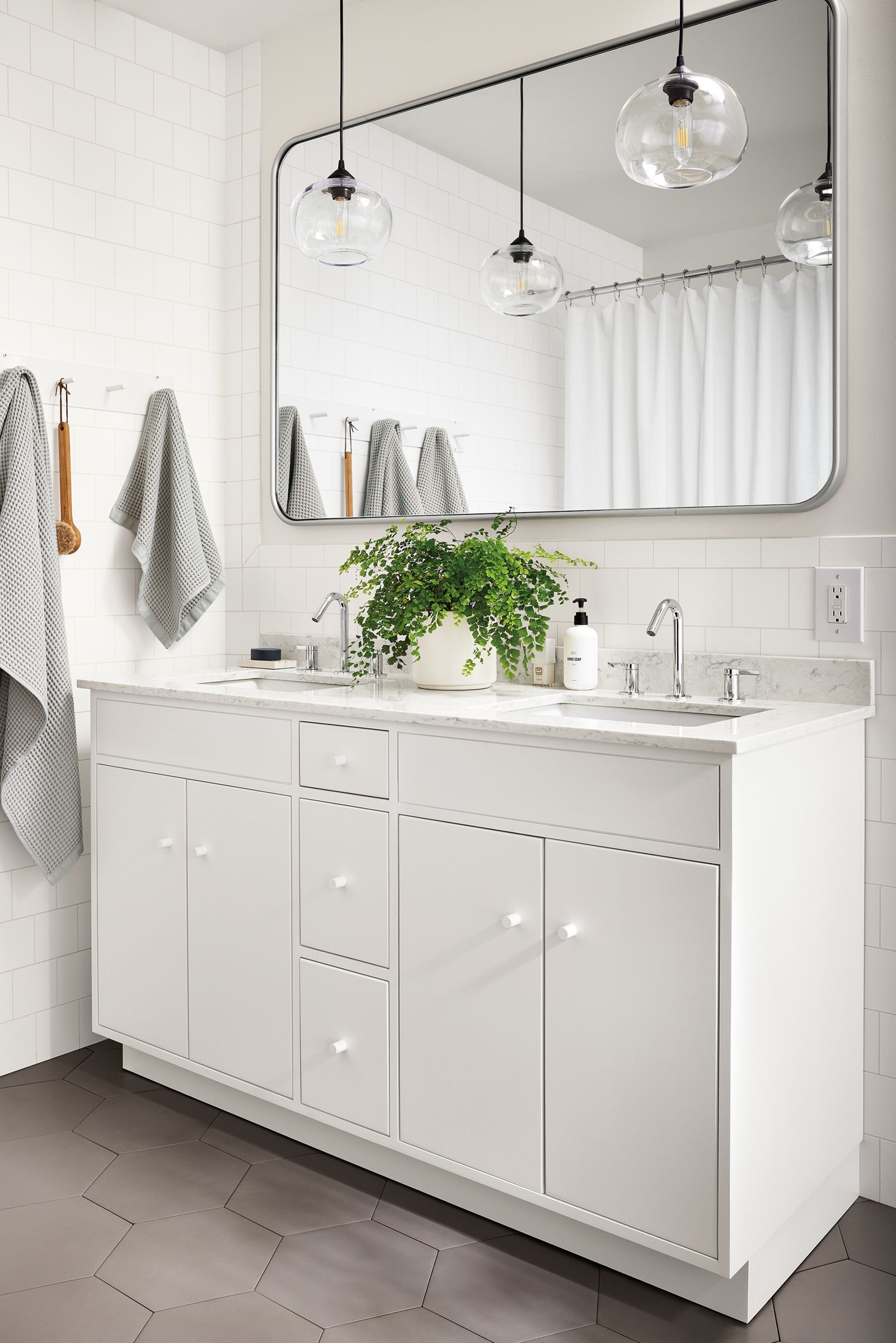 bathroom with linear vanity in white with marbled white quartz top, lyndale mirror, sky pendants