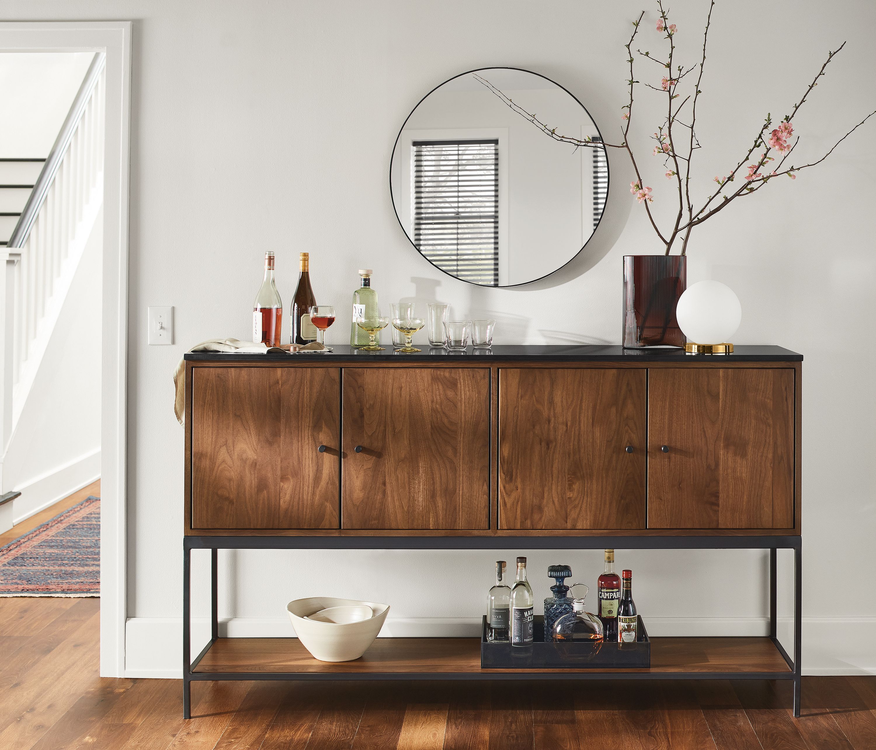 Living area with Linear 72-wide storage cabinet in walnut with black quartz top and Infinity round mirror in graphite.