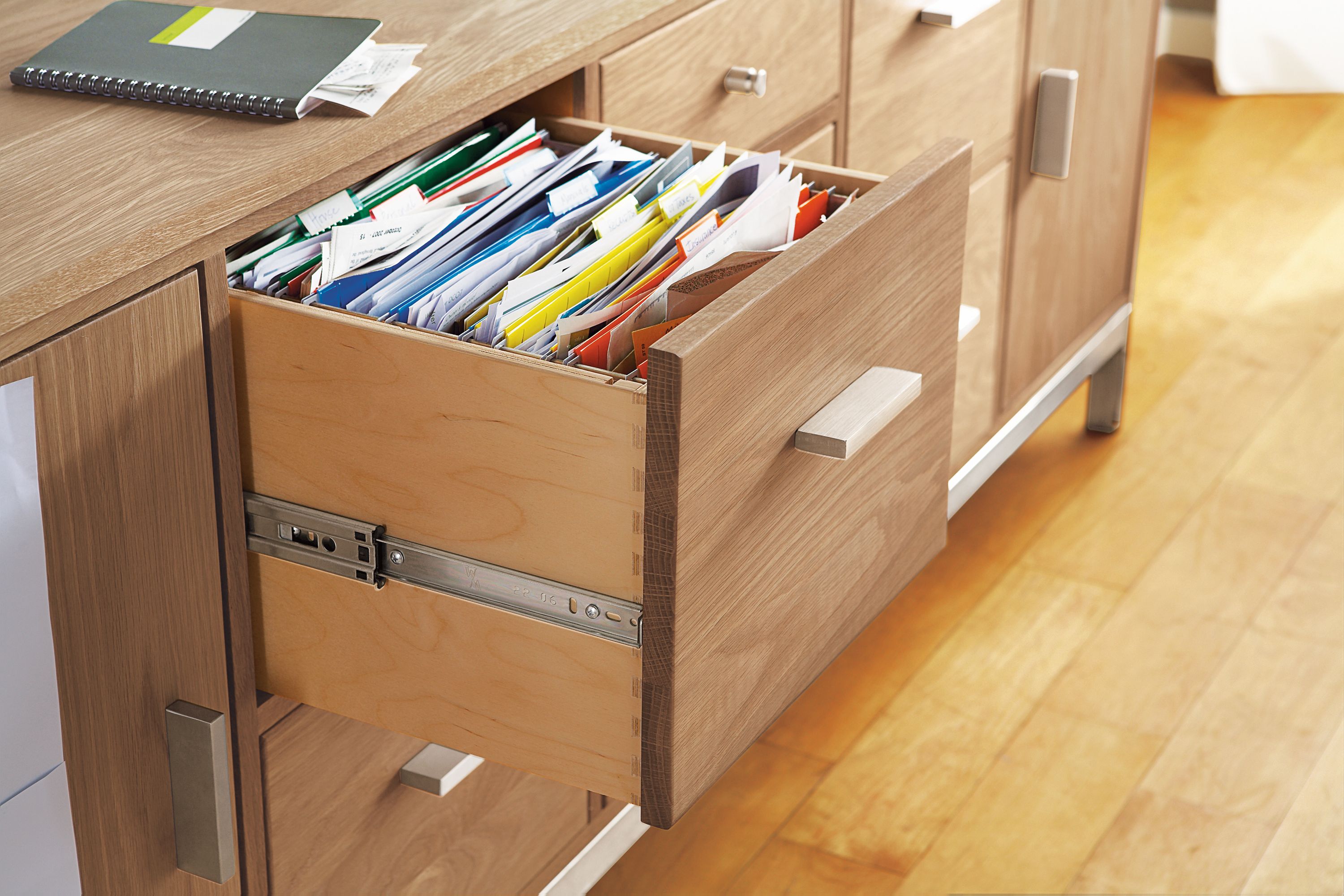 Detail of file drawer on Linear 83-wide office storage cabinet in rye on red oak and stainless steel.
