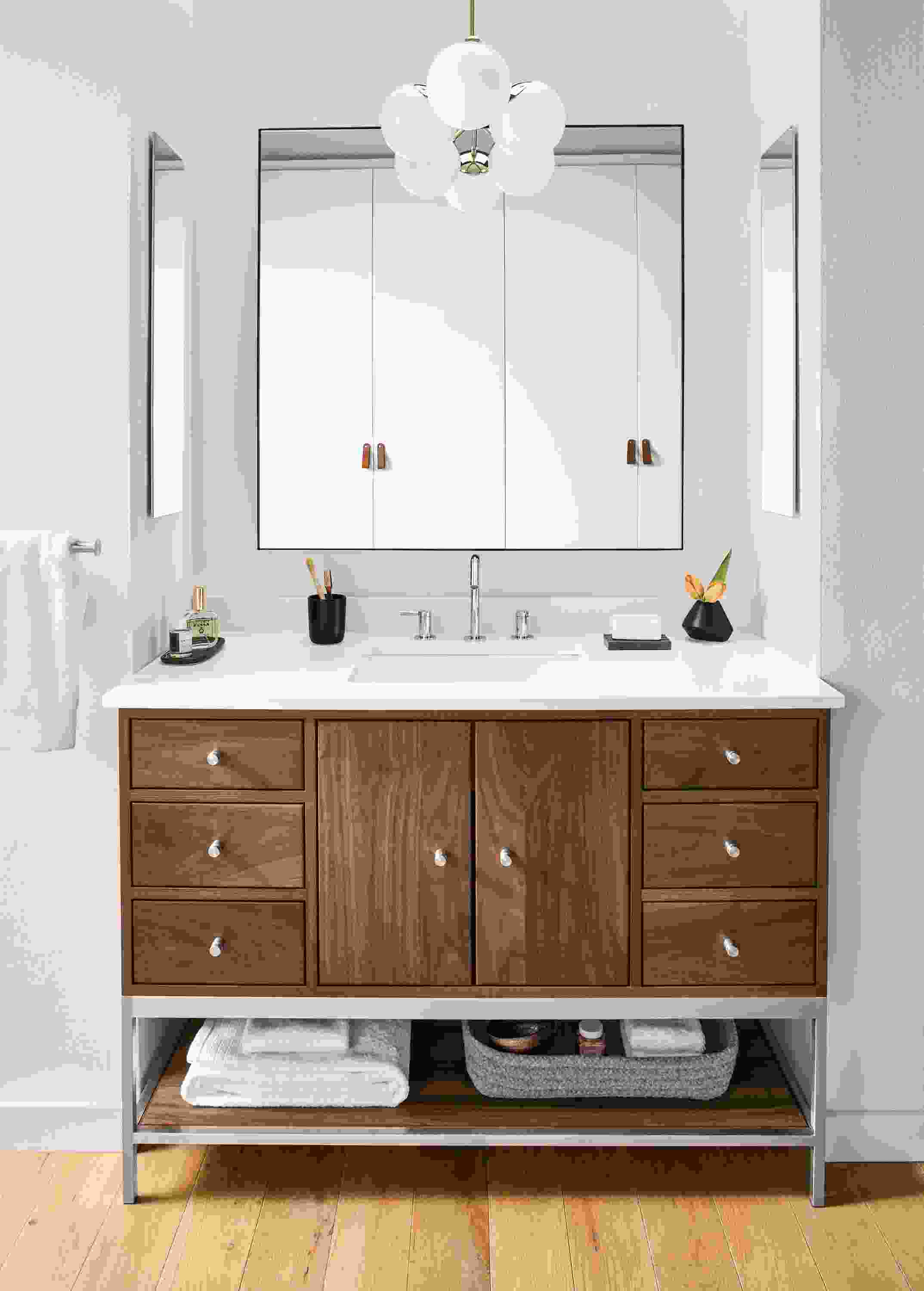 Detail of Linear bathroom vanity in walnut and stainless steel in bathroom.