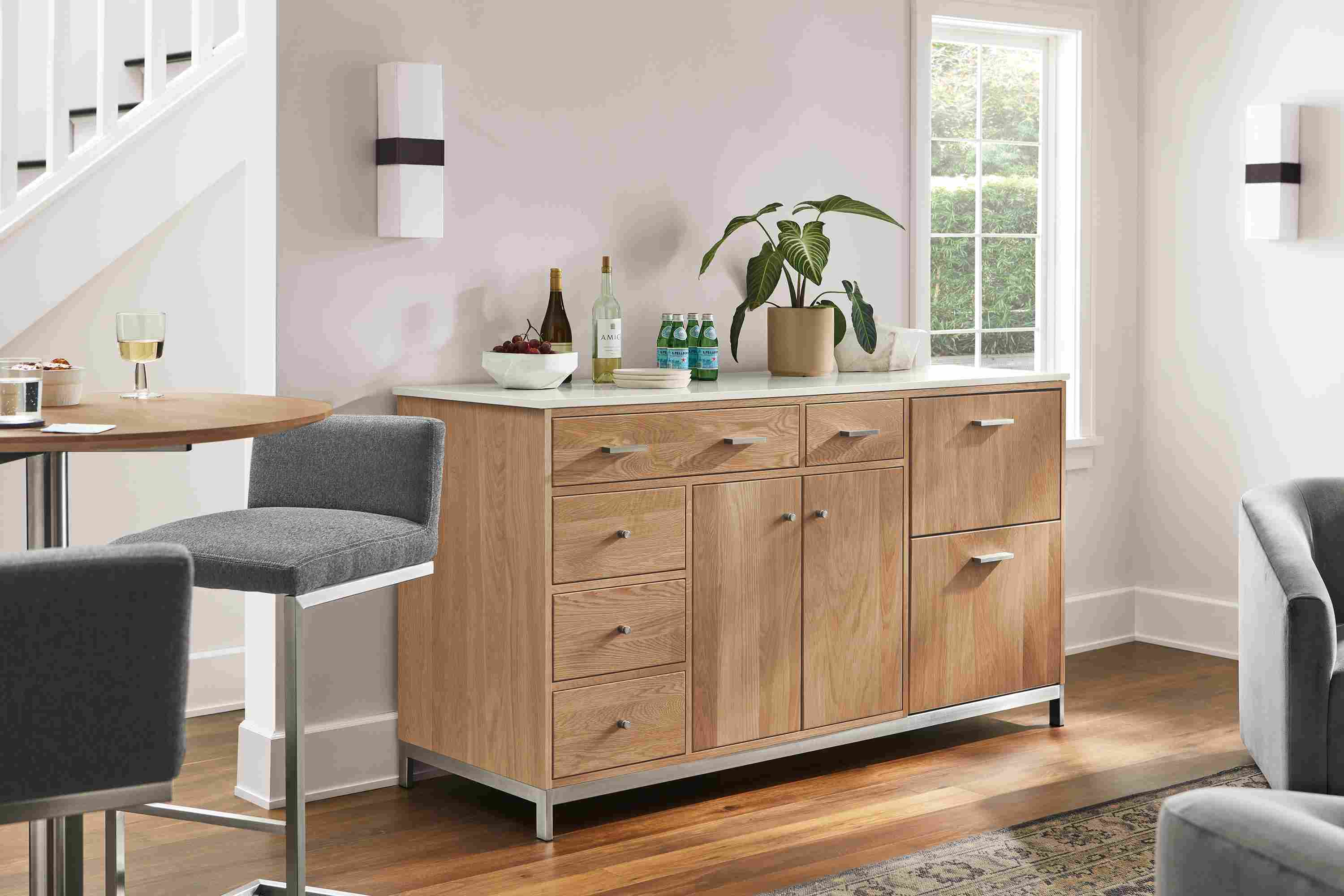 Living room with Linear 72-wide storage cabinet in rye on red oak with refrigeration, Lira stools, Iris sconces.