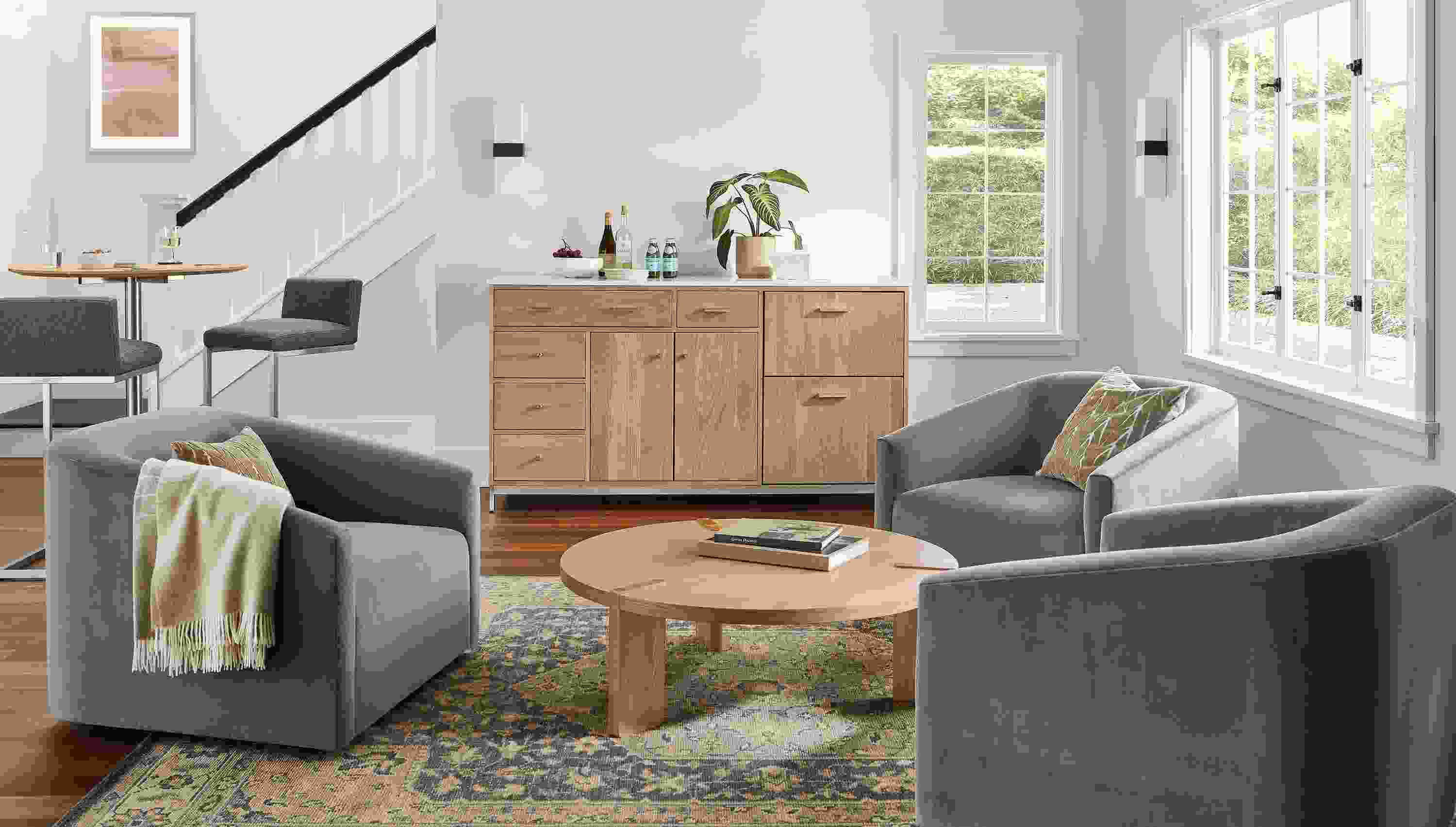 Living room with Linear 72-wide storage cabinet in white oak with refrigeration, Ada swivel chairs, Hanover coffee table.