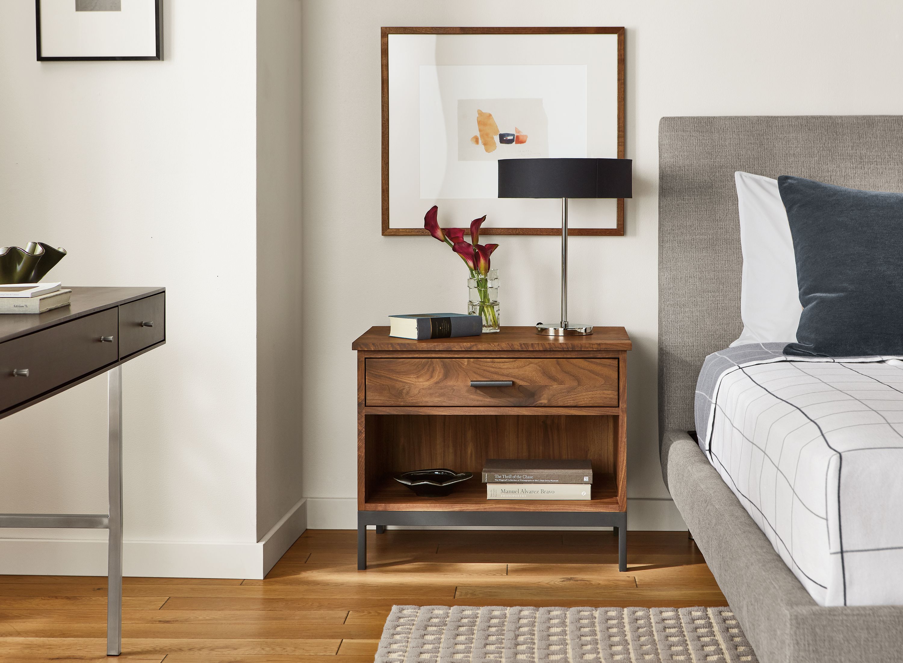 Bedroom with Linear nightstand in walnut beside Ella bed, Cohen table lamp, Julius Bissier artwork.