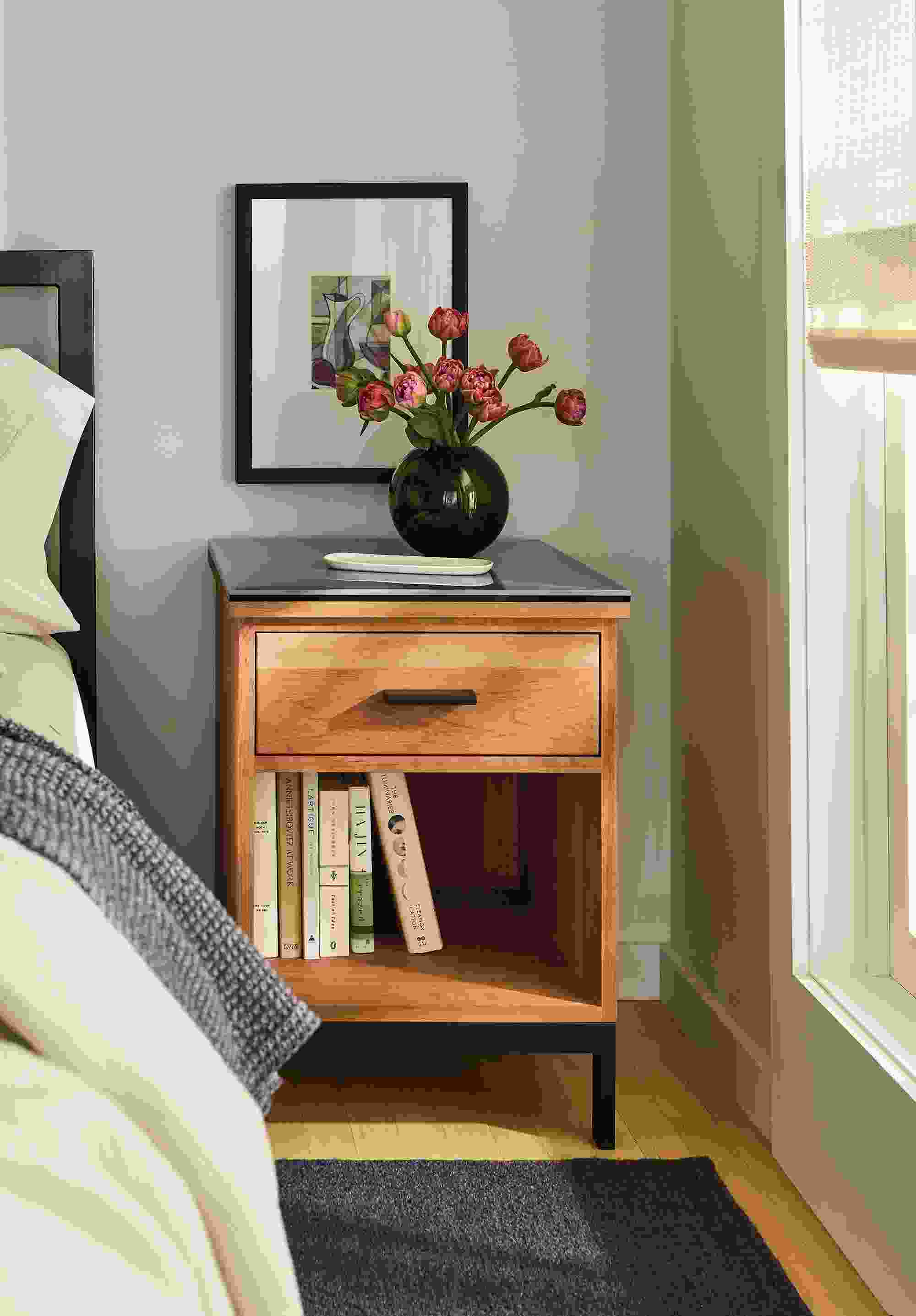 Bedroom showing a detail of linear one-drawer nightstand with marbled grey ceramic and Avilia rug in charcoal.