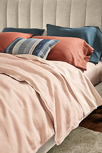 detail of colorful percale and linen bedding on bed.