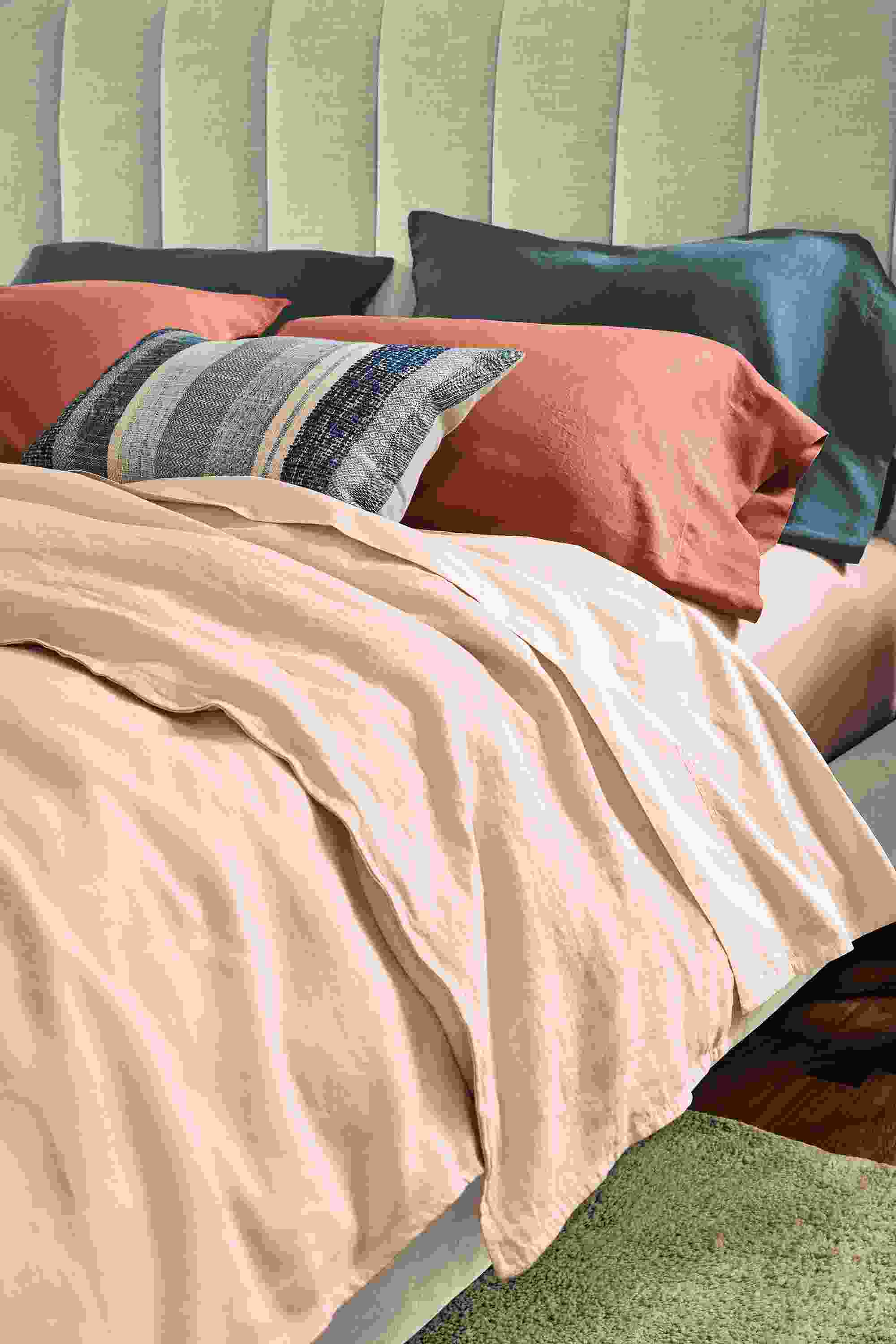 detail of colorful percale and linen bedding on bed.