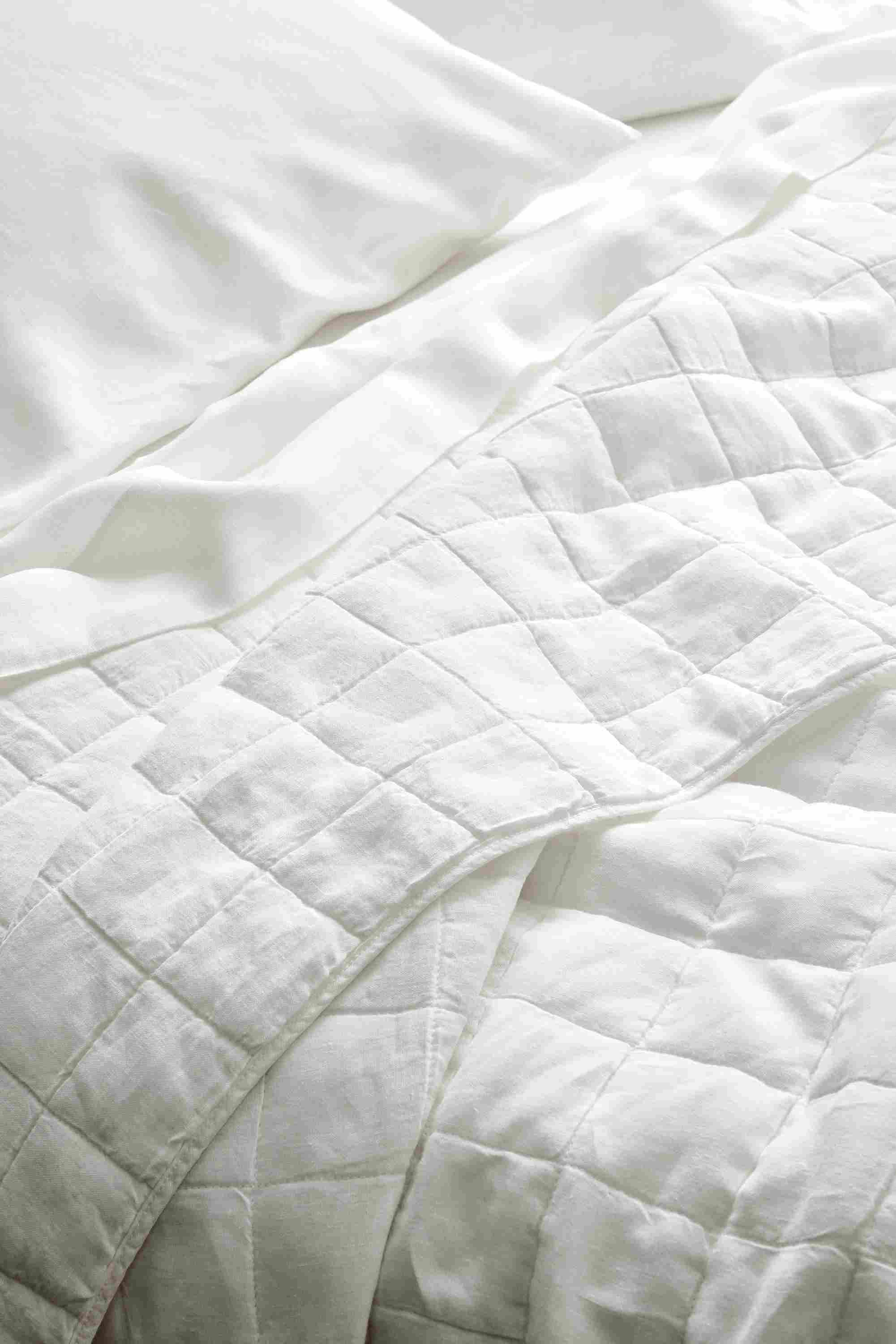Close-up of relaxed linen full/queen quilted coverlet and relaxed linen queen sheet set in white.
